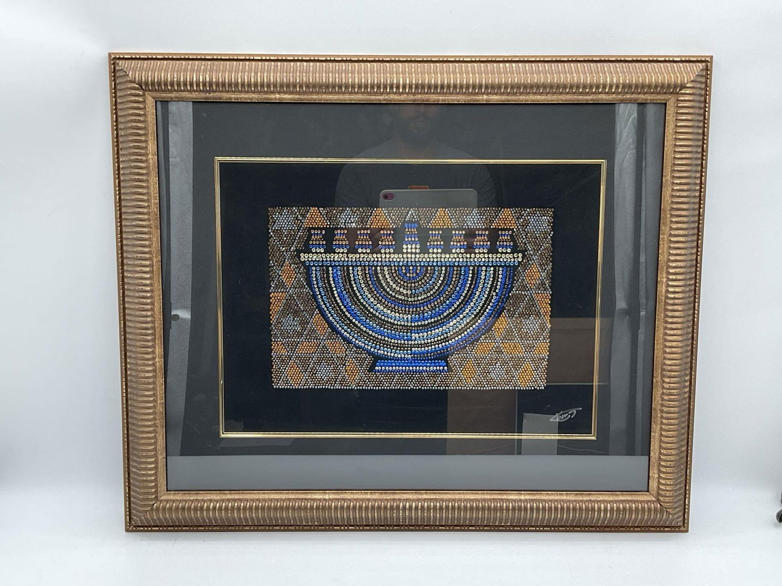 Rhinestone Menorah and Star of David Swarovski Mosaic Artwork - Artist Mordechai: Framed rhinestone mosaic depicting a menorah beneath a radiant arch, accented by repeating Star of David patterns in gold, silver, and blue tones. The piece is presented on black velvet and enclosed i