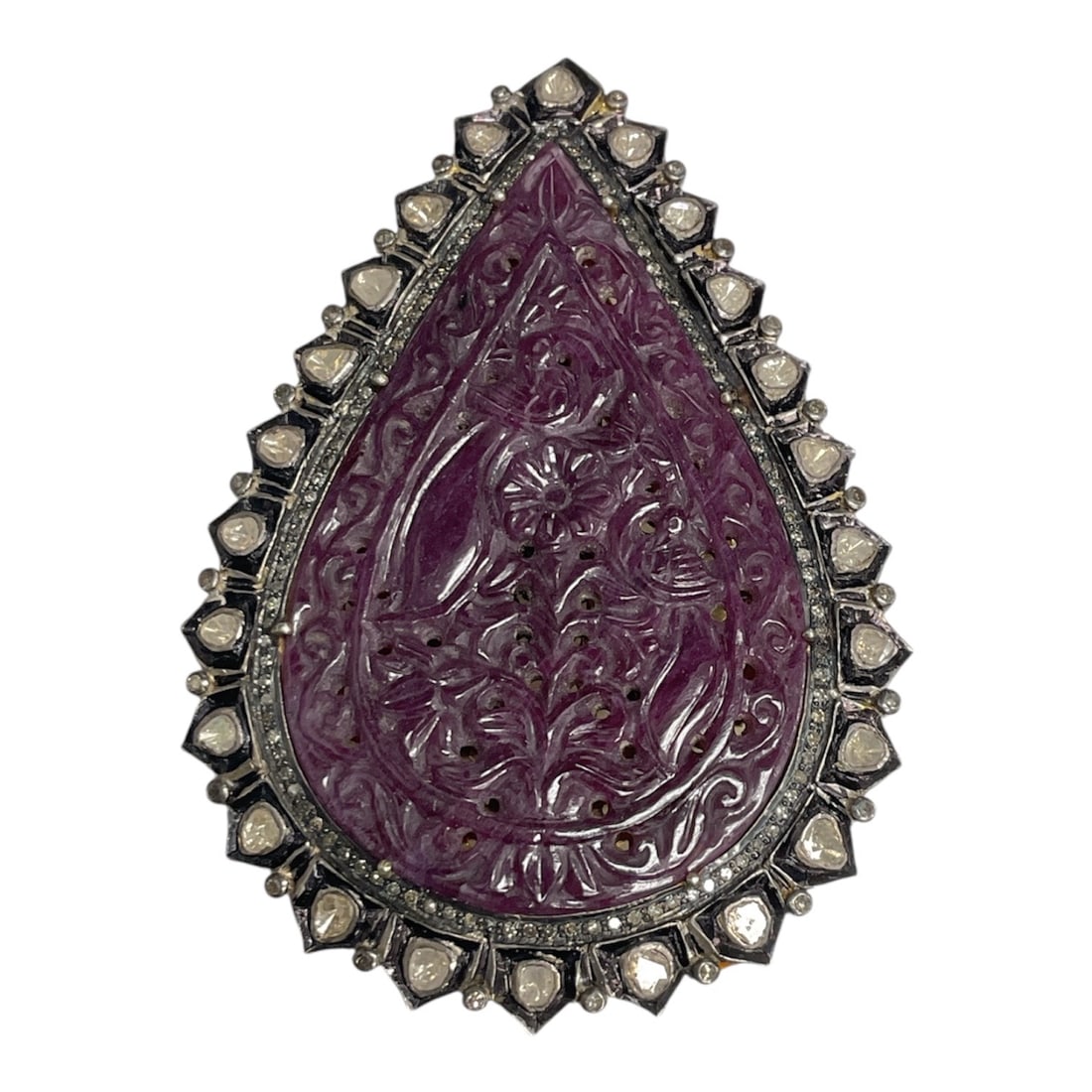 Antique Style Teardrop Carved Purple Hardstone Marcasite Brooch Pendant: This antique-style brooch features a teardrop-shaped carved purple hardstone centerpiece with intricate floral and scrollwork detailing. The stone is framed by a border of faceted marcasite-style acce