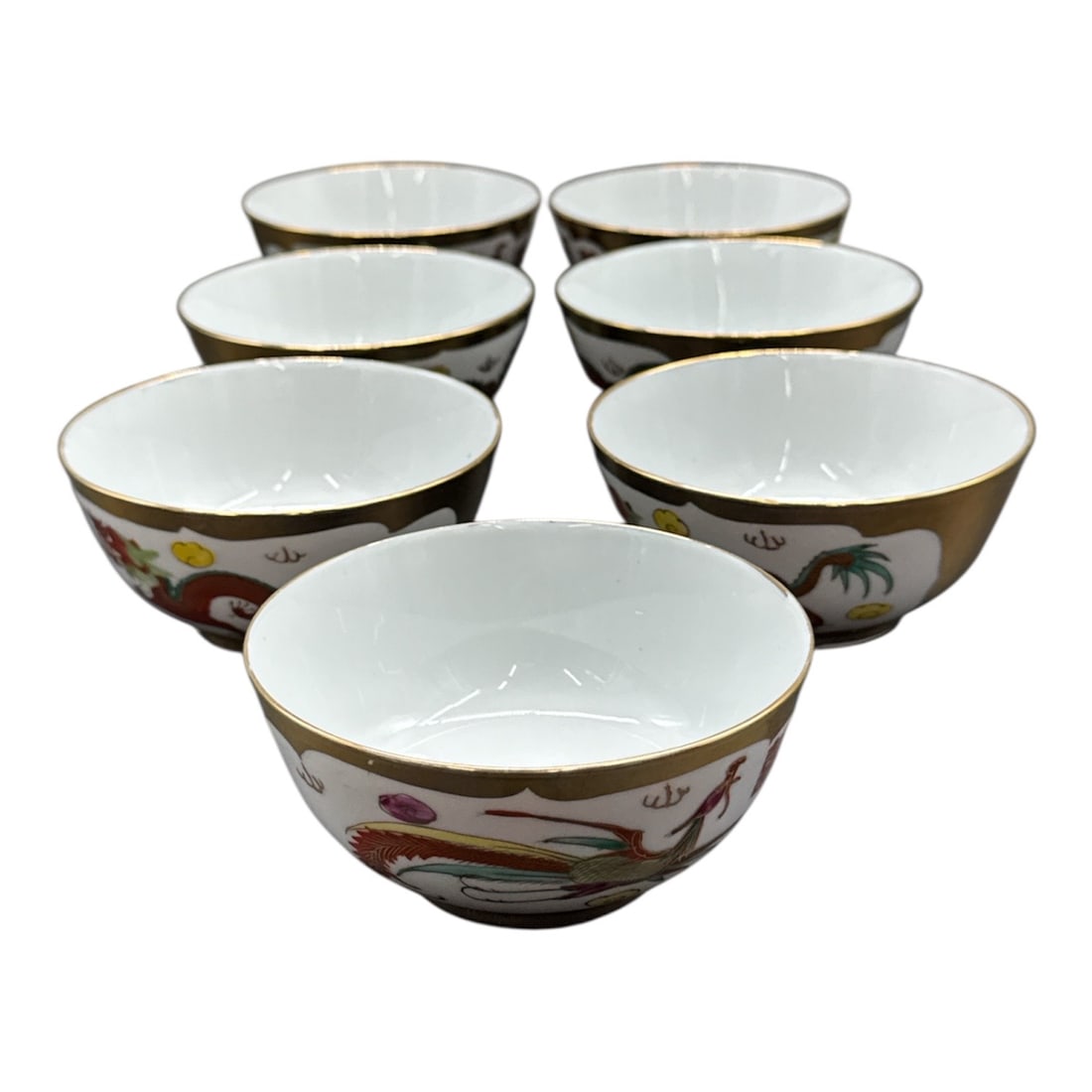 Set of 7 Chinese Porcelain Dragon and Phoenix Bowls with Gilt Rim: Decorative set of seven small porcelain bowls made in China, each featuring vibrant dragon and phoenix motifs with colorful enamel detailing and wide gilt borders alon