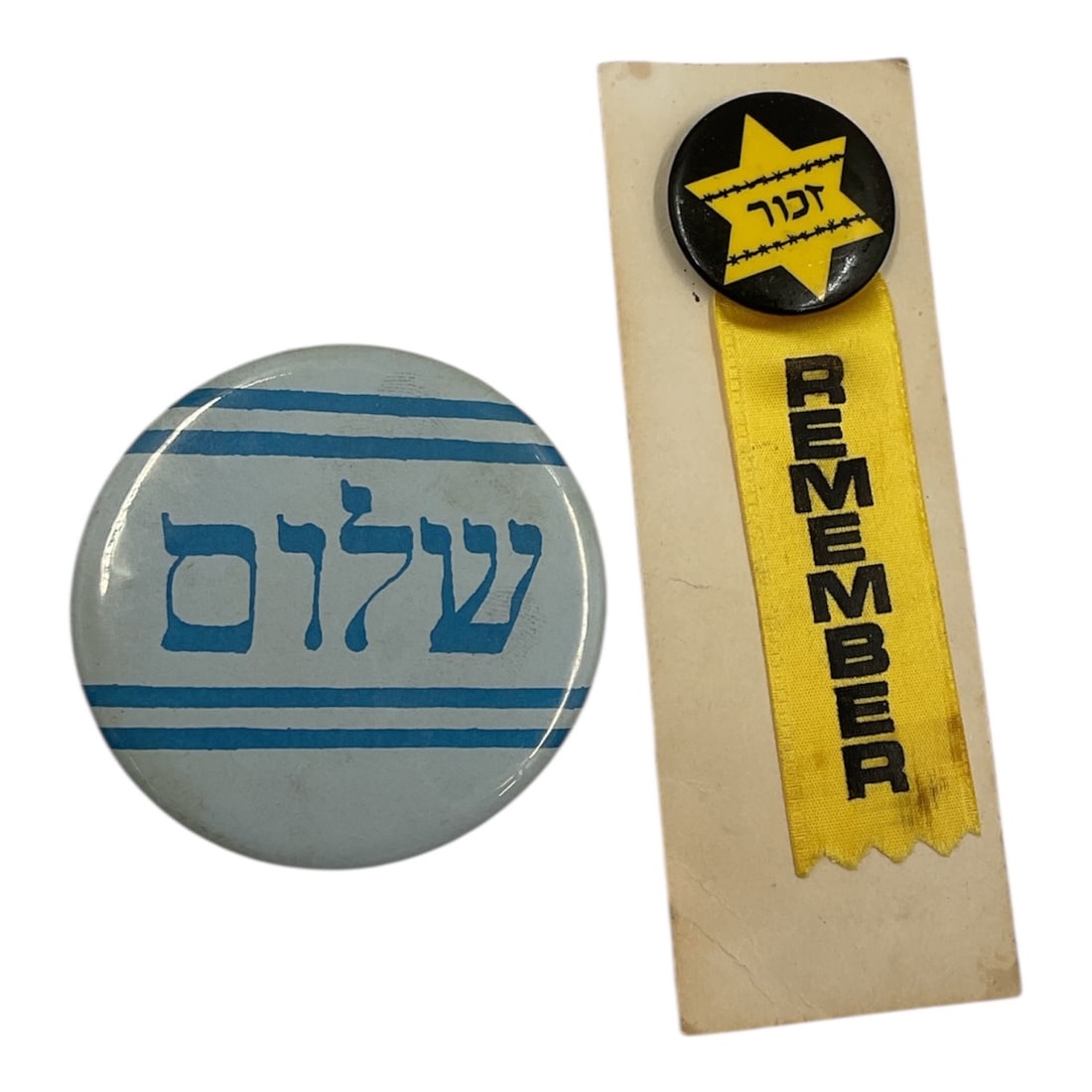 Holocaust Remembrance Ribbon Pin Zachor with Sholom Pinback: Commemorative grouping including a ribbon pin featuring a yellow star badge with the word Jude and a hanging ribbon reading Zachor meaning remember, a symbol associated with Holocaust remembrance. Acc