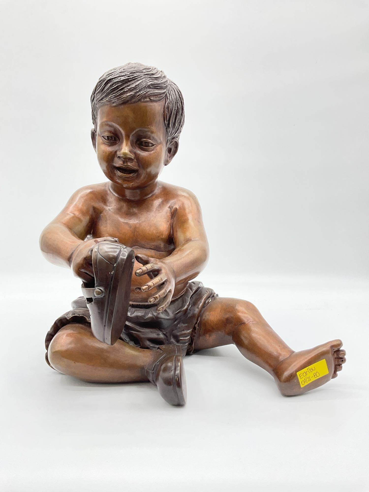 Bronze sculpture boy tying shoe by Leonardo Rossi: Realistic bronze sculpture of a young boy seated and tying his shoe, signed by Italian artist Leonardo Rossi. Detailed craftsmanship with smooth patina and lifelike features, capturing a candid childh