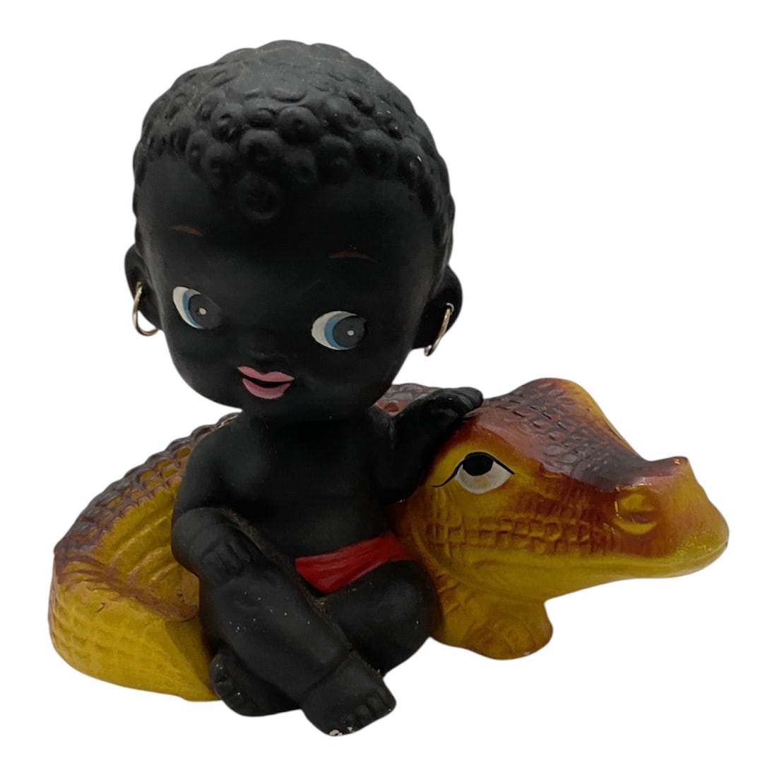 Black Americana Boy on Alligator Nodder, Mid-20th Century: A vintage figural bobblehead (nodder) depicting a child seated atop an alligator, rendered in bright painted colors with stylized features. The figure features a spring-mounted head designed to nod wi