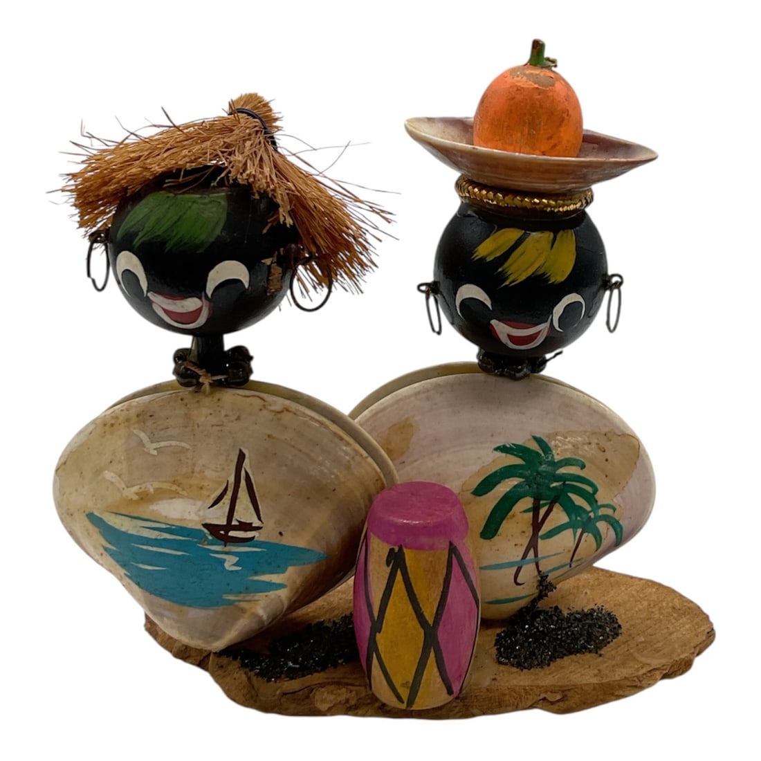 Black Americana Shell Figural Couple Souvenir Sculpture, Made in Japan, Mid-20th Century: A vintage figural souvenir sculpture depicting a couple in a tropical setting, constructed with shell bodies and hand-painted composite heads. The figures are adorned with decorative elements includin