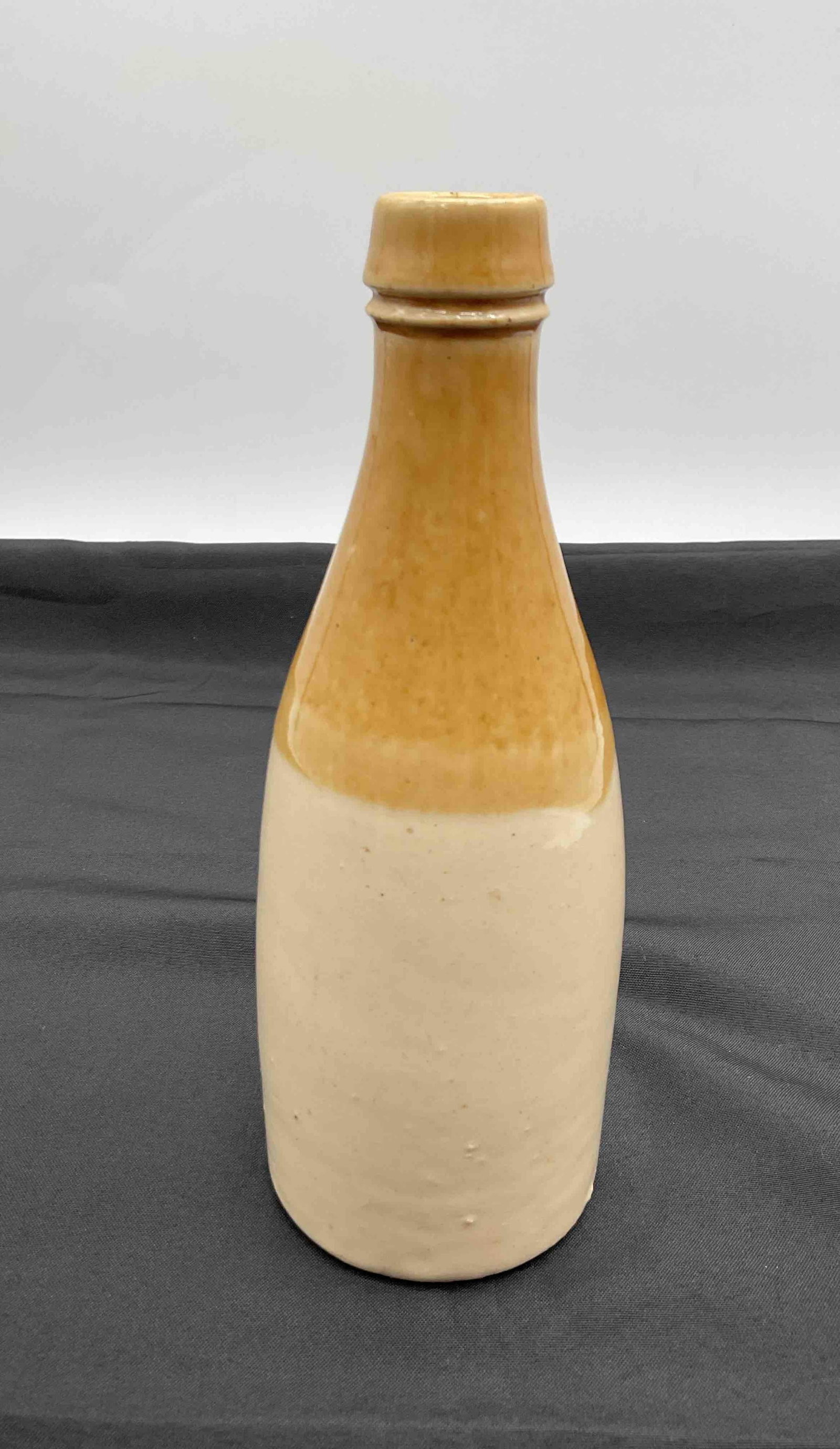 Civil War Era Stoneware Beer Bottle: Antique stoneware beer bottle with two-tone salt-glazed finish in tan and cream. Typical of mid-19th century utilitarian wares used during the Civil War period. Shows wear consistent with age and use.