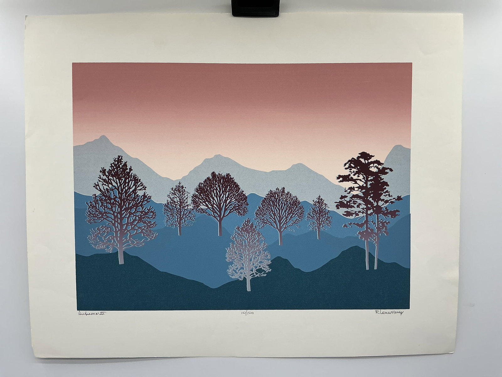 R. Lownsbery 'Autumn III' Print 10/100: R. Lownsbery, 'Autumn III', print, numbered 10/100, signed lower right. The print depicts a landscape with trees and mountains in shades of blue, pink, and purple. Matted and framed.