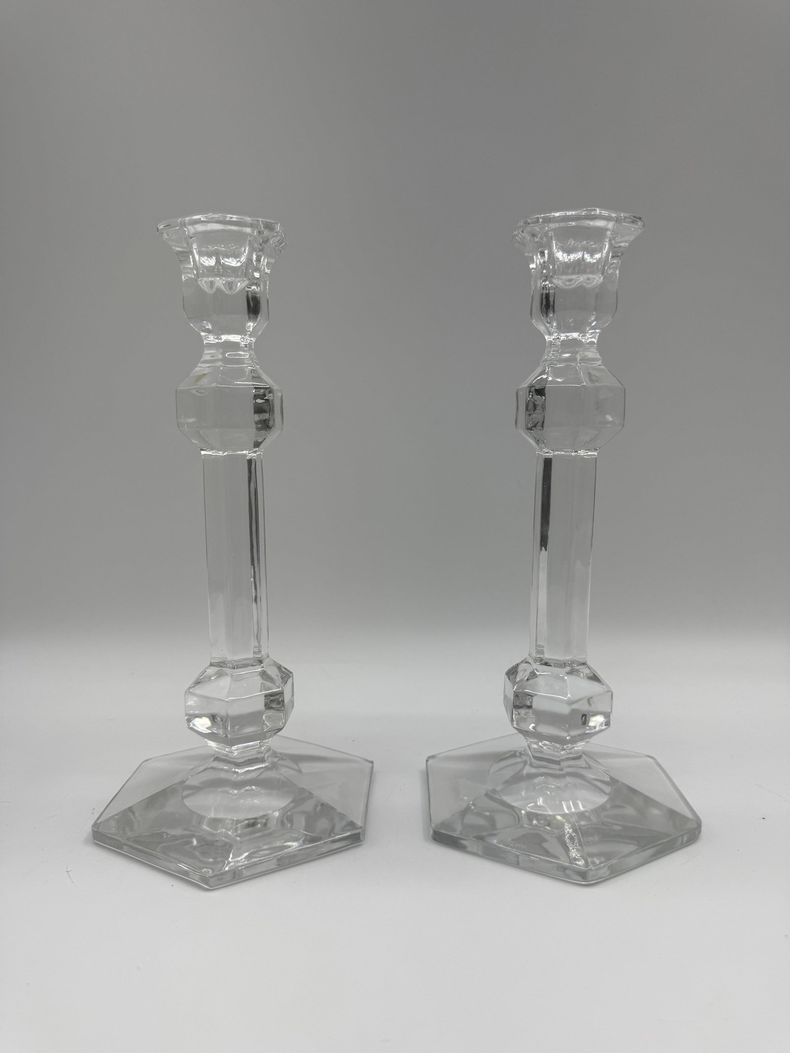 Pair of Irena Crystal Candlestick Holders: Pair of clear crystal candlestick holders by Irena. Each features a hexagonal base and a faceted design. Elegant and functional, perfect for adding a touch of sophistication to any table setting.