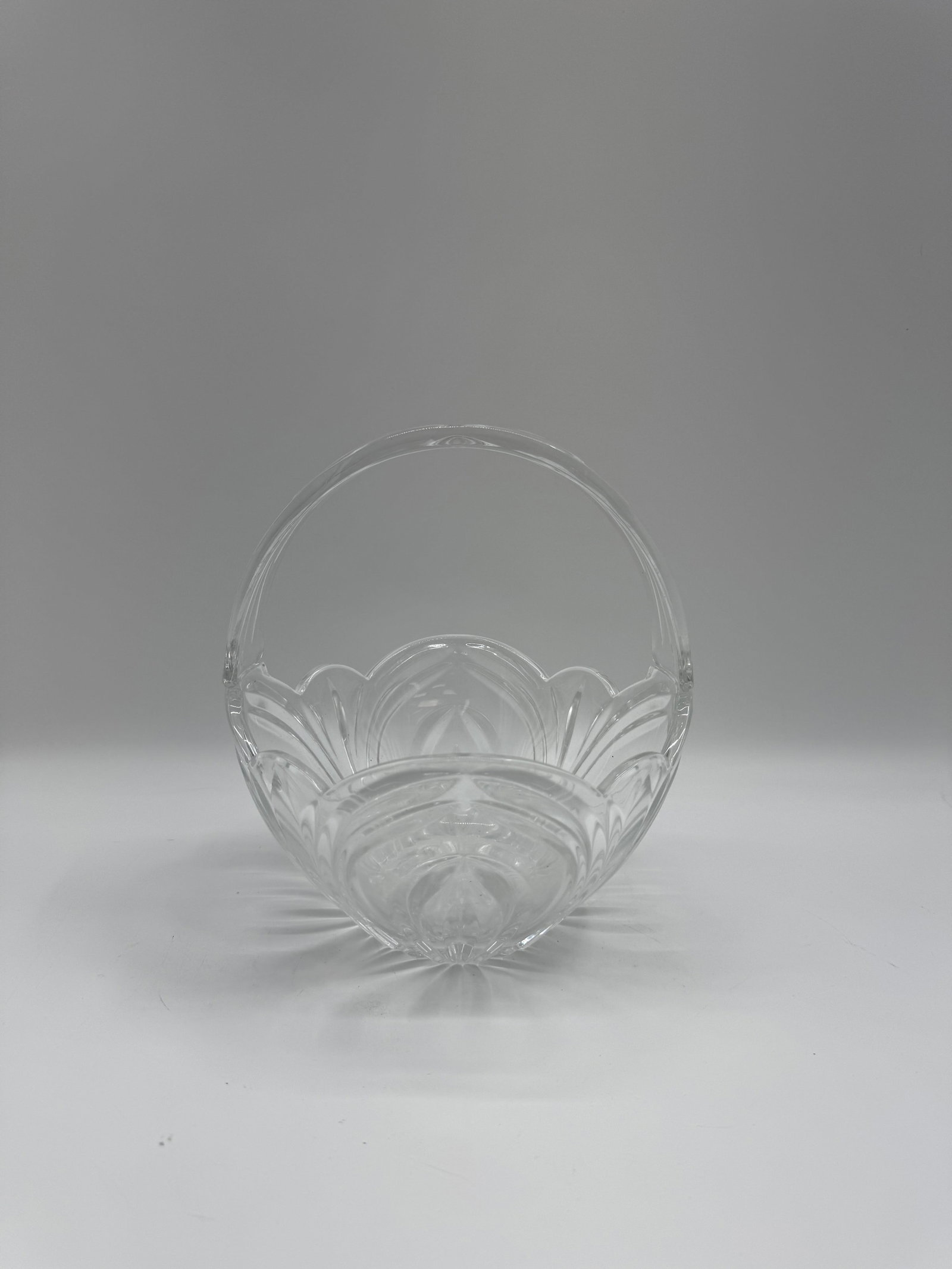 Cut Crystal Basket with Handle: A clear cut crystal basket featuring a decorative handle and intricate cut designs. The basket is in good condition and would make a lovely addition to any home.