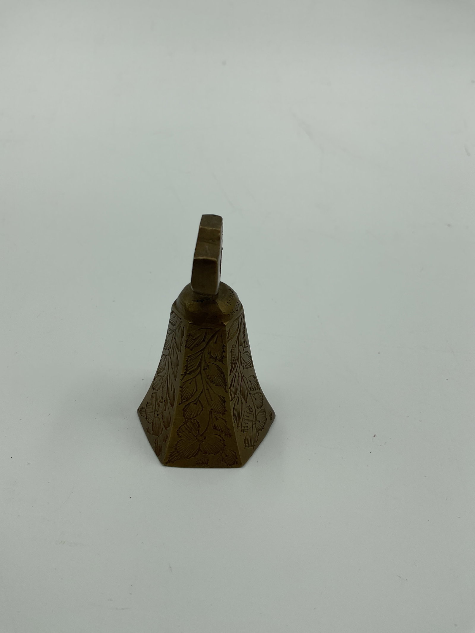 Engraved Brass Hand Bell: Small brass hand bell with engraved floral designs. Measures approximately 2.75 inches in height and 1.5 inches in diameter.