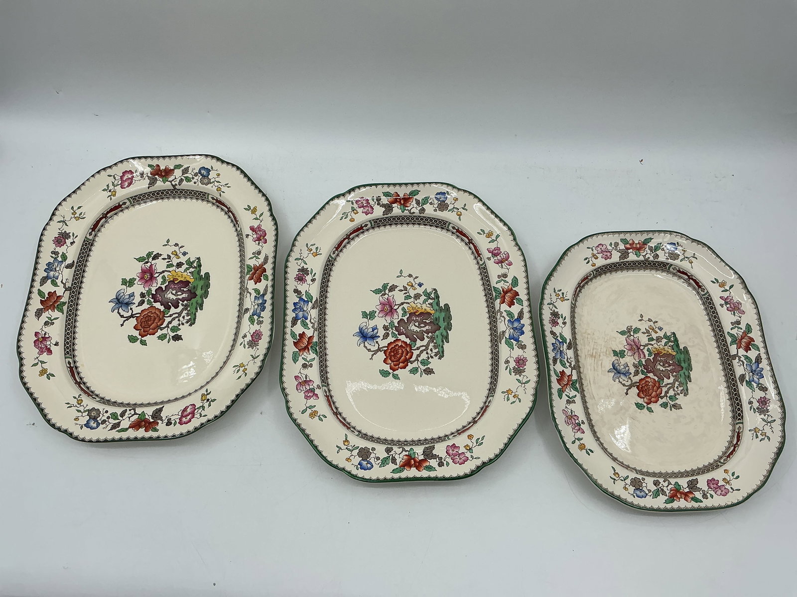 Spode England Chinese Rose Plates, Set of Three: Set of three Spode England 'Chinese Rose' pattern plates. Includes two large plates (1.5" x 14" x 11") and one small plate (1.5" x 12.5" x 9.5"). Floral design wi
