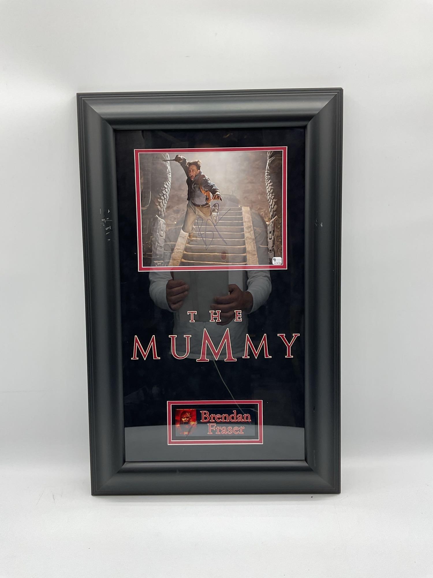 Brendan Fraser The Mummy Framed Autograph: Framed color photo of Brendan Fraser in an action scene from The Mummy, signed in blue ink. Includes the movie title and a nameplate with the actor’s name. Dimensions: H28in L18in Medium: M