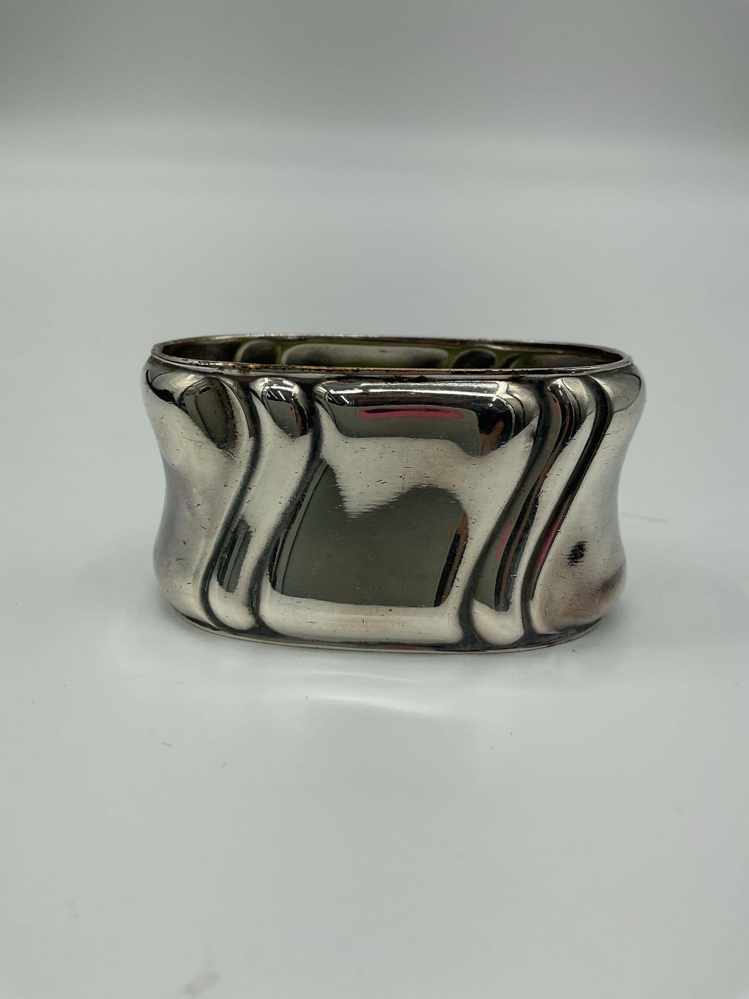 Vintage Silver Napkin Ring with Wavy Edge Design: This is a vintage silver-plated napkin ring featuring a unique wavy or scalloped edge design. The ring has a smooth, polished finish with a modernist flair, likely dating from the mid to late 20th cen