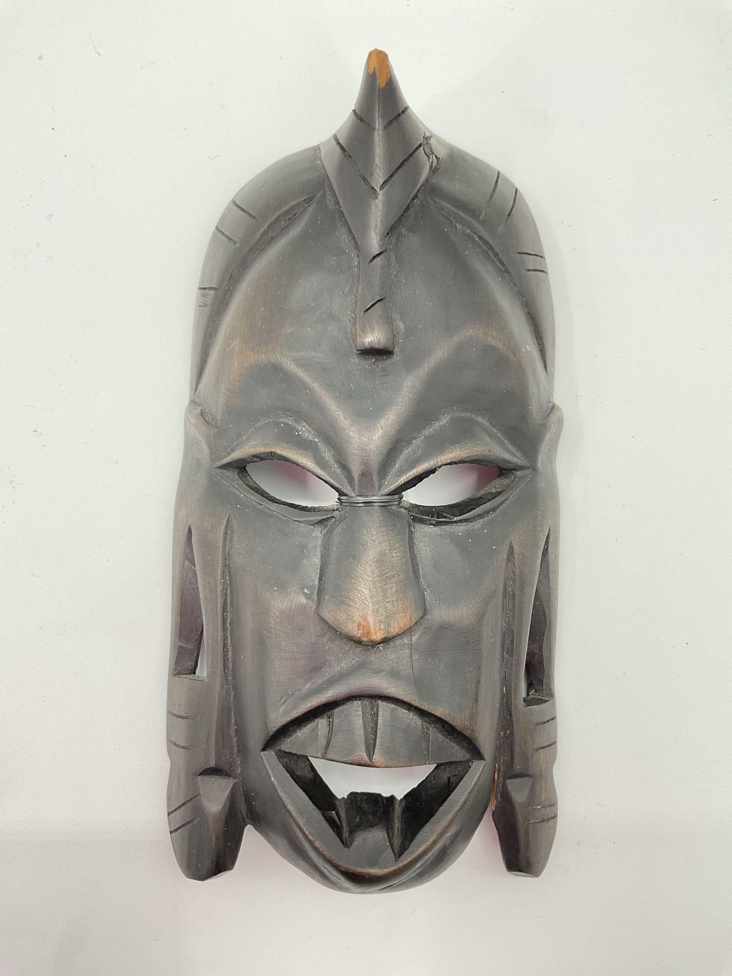 Hand-Carved African Tribal Mask - Box 4: A dark hardwood hand-carved African tribal mask featuring bold geometric facial features, deep-set eyes, and an open mouth with sculpted teeth. The mask has intricate carvings along the forehead and s