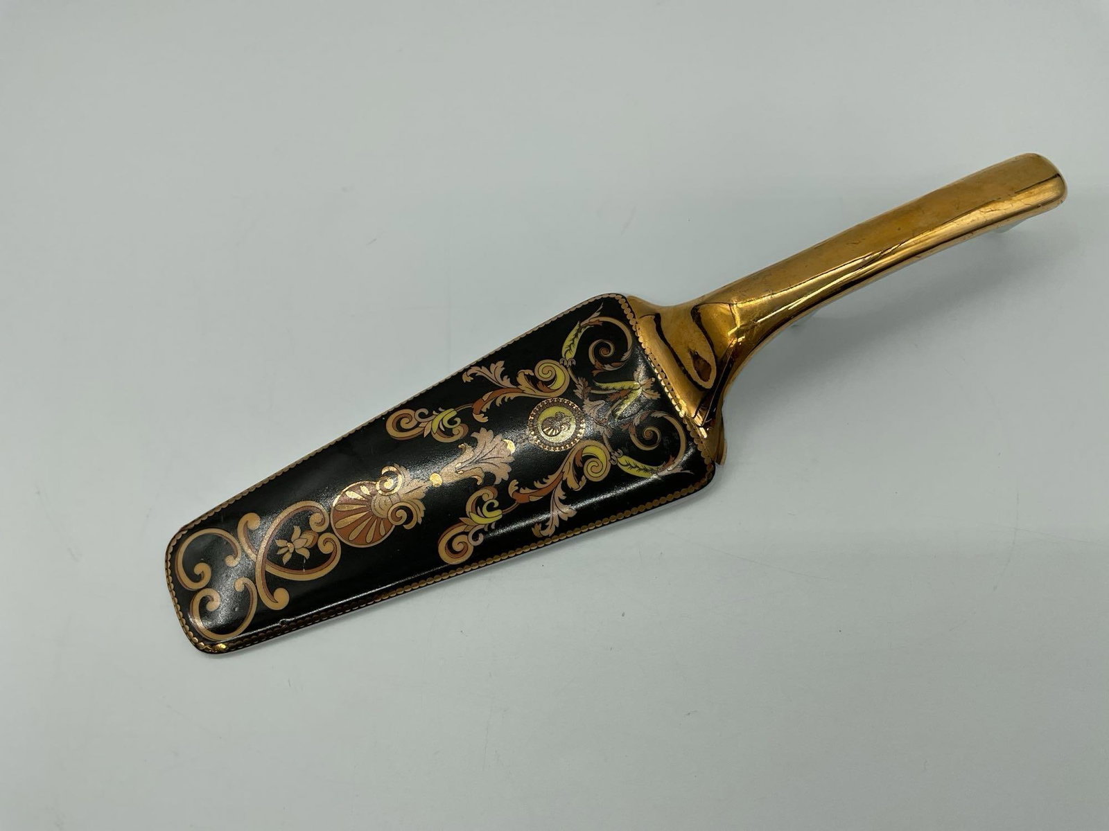 Decorative Italian Style Ceramic Cake Server: Elegant cake server with a glossy gold tone handle and a black serving surface adorned with ornate scroll and floral motifs in orange, yellow, and beige. A striking piece ideal for both functional use