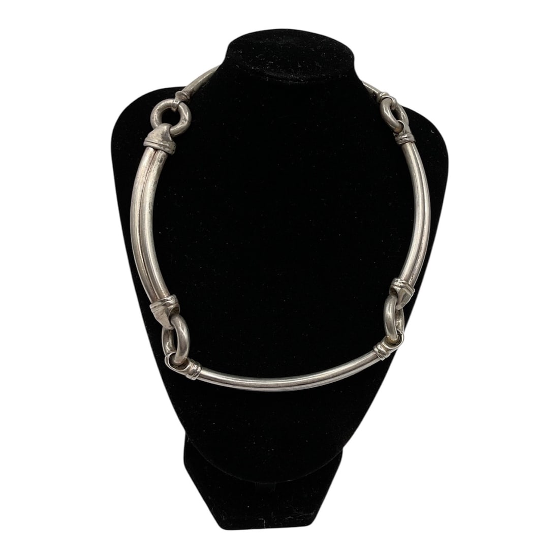 Silver Tone Tubular Link Choker Necklace: Bold choker necklace featuring a tubular link design with curved segments connected by circular rings. The piece has a clean, modernist aesthetic with a structured form that sits prominently along the