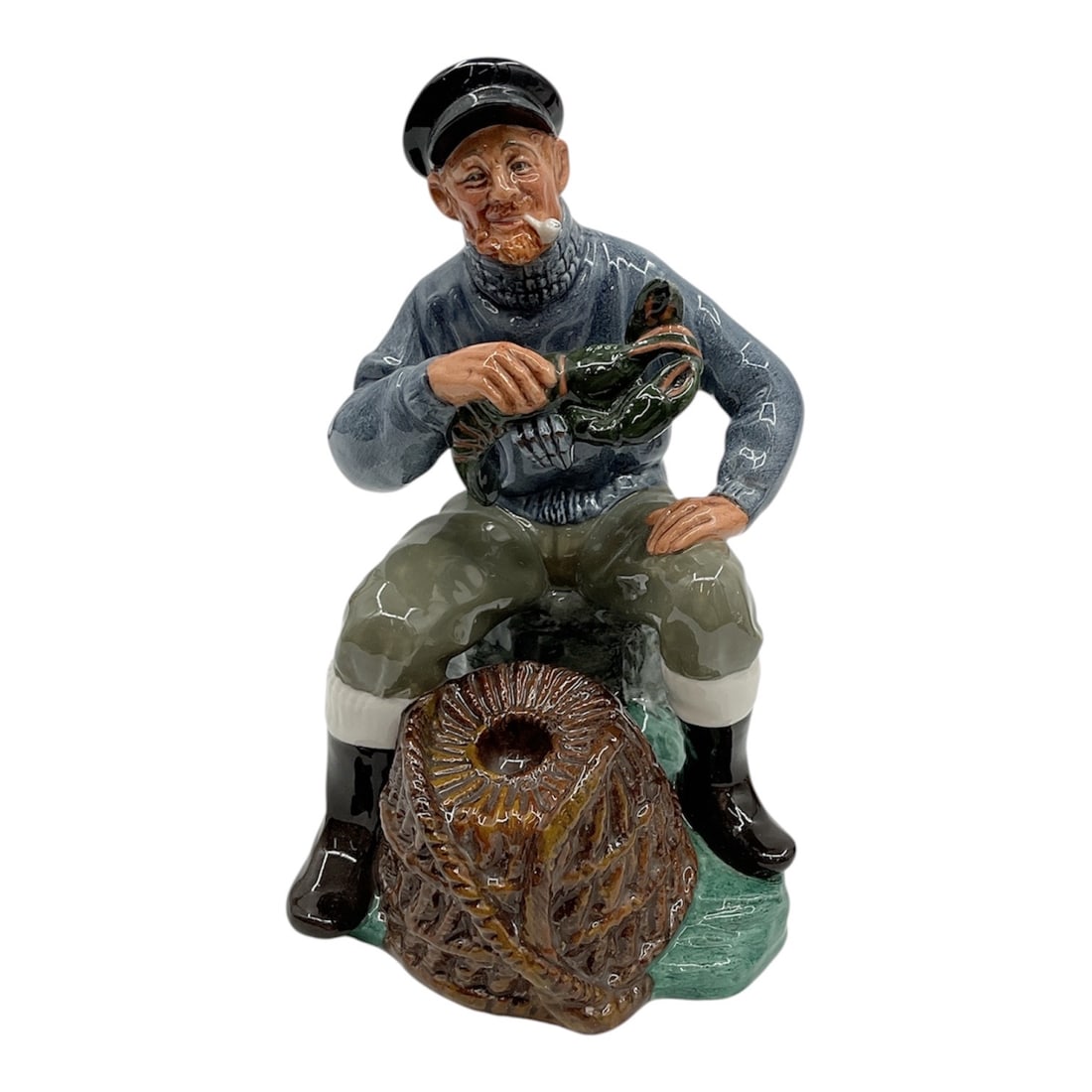 “The Lobster Man?? Figurine, Royal Doulton: A finely detailed Royal Doulton porcelain figurine titled The Lobster Man, depicting a seated fisherman holding his catch beside a lobster trap. The piece is richly hand-paint