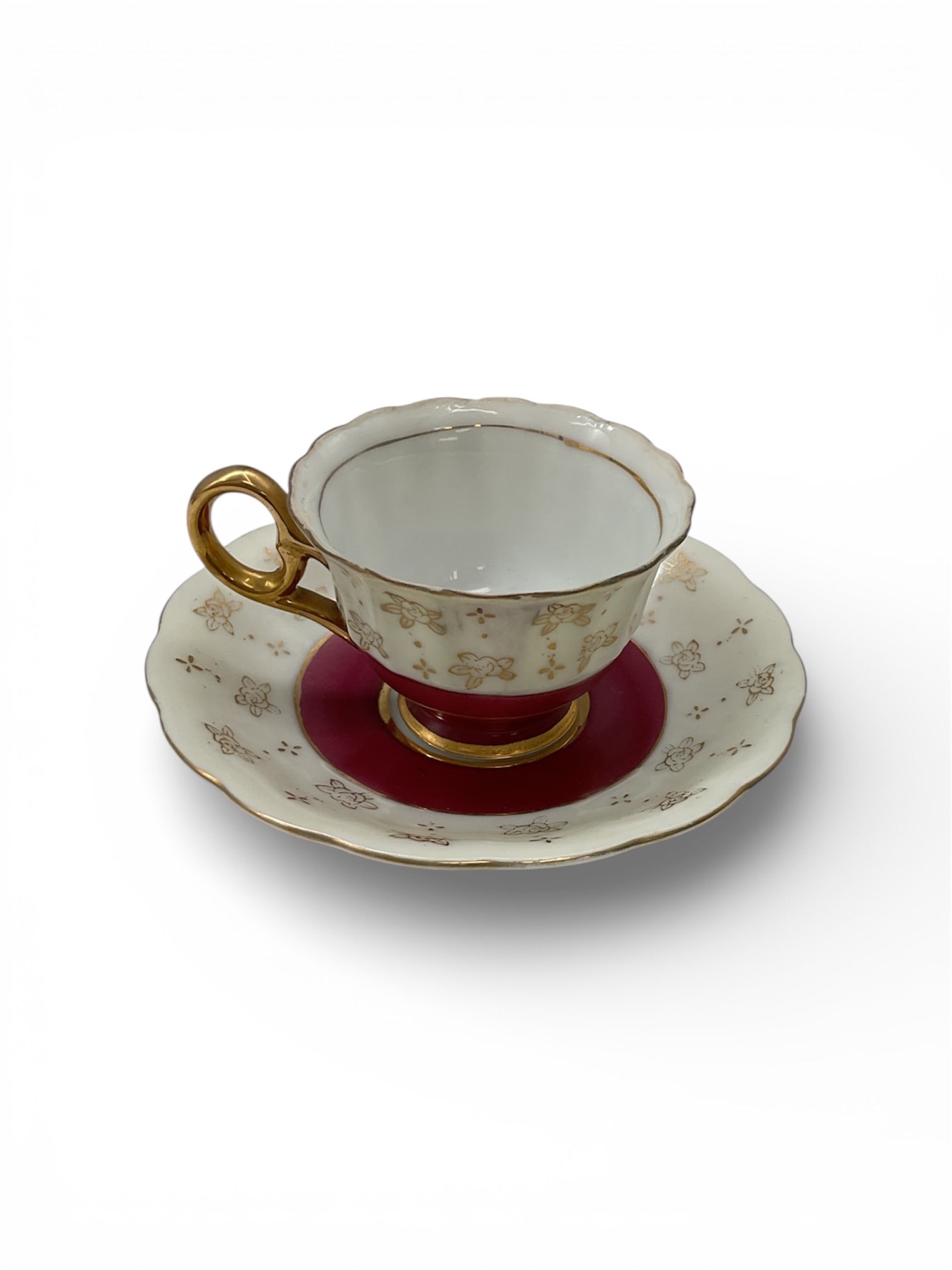 Made in Japan Porcelain Demitasse Cup and Saucer with Gilt and Red Well: This porcelain demitasse cup and saucer set was made in Japan for export and features an elegant ivory ground decorated with delicate gilt floral accents. The saucer is centered with a rich red well b