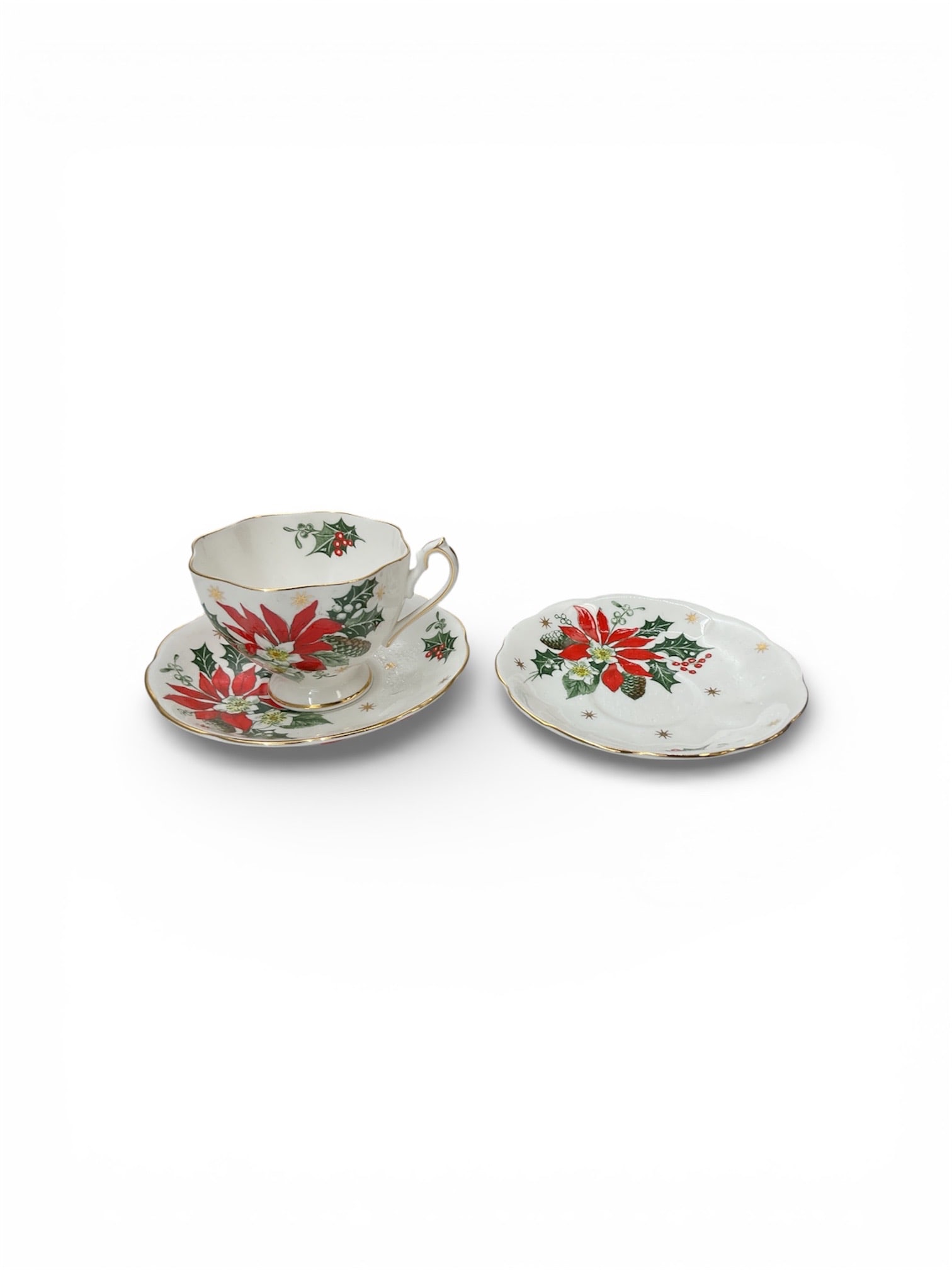 Noel Pattern Queen Anne Fine Bone China Demitasse Cup and Saucer: This fine bone china demitasse cup and saucer set is from the Noel pattern by Queen Anne and features a festive poinsettia motif rendered in rich red and green tones against a white ground. The cup di