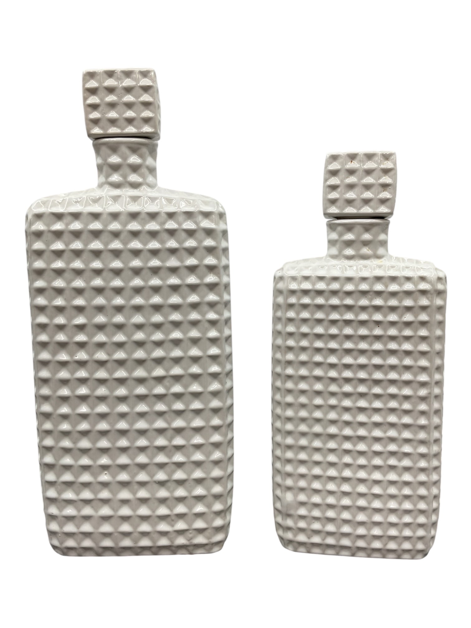 Pair of White Glazed Ceramic Textured Decorative Bottles: A matching pair of contemporary ceramic decorative bottles featuring a crisp white glazed finish and a repeating raised geometric stud pattern across the body and stopper. Each bottle has a rectangula