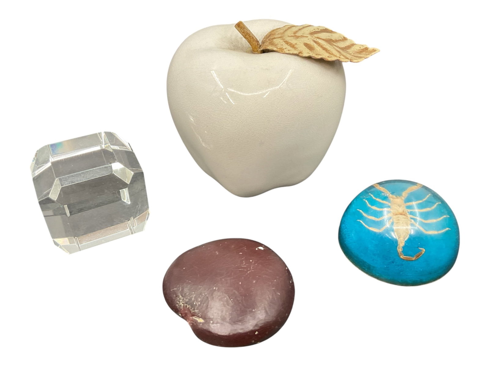 Collection of Decorative Desk Objects Including Crystal and Ceramic Apple: Assorted collection of decorative tabletop and desk accessories including a faceted clear crystal paperweight, glazed ceramic apple with metallic leaf accent, polished stone specimen, and blue resin o