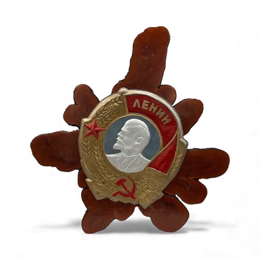 Soviet Lenin Badge on Carved Wood Backing: A large wood carving depicting the Order of Lenin, featuring a central medallion with Lenin's profile, a red star, and a hammer and sickle. The carving is mounted on a starburst-shaped wooden base