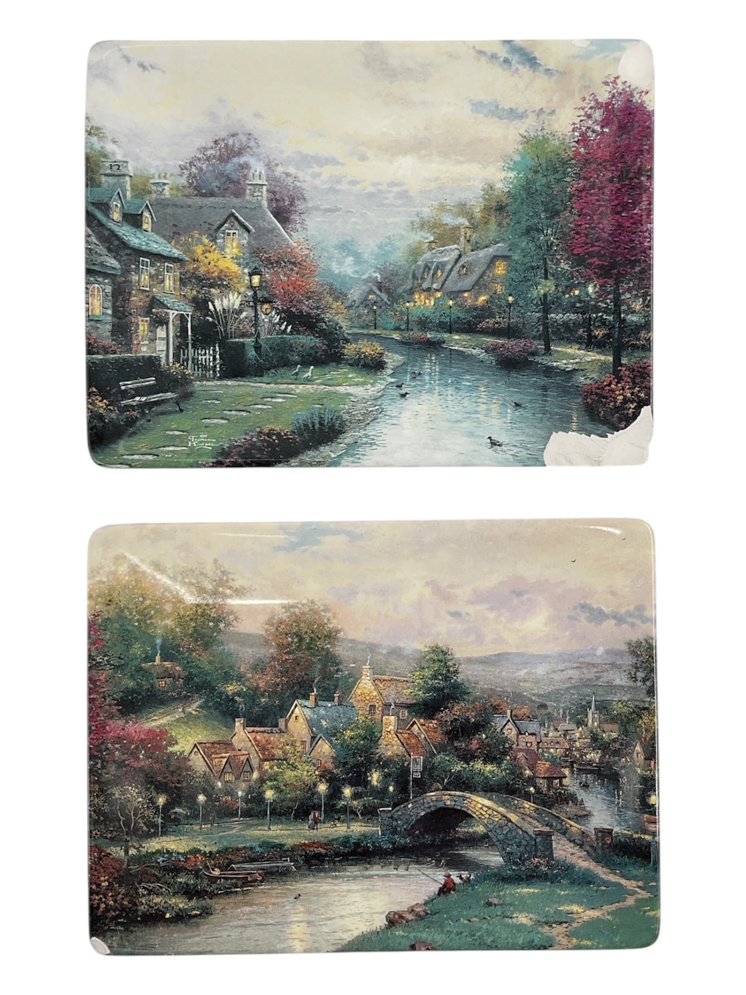 Pair of Thomas Kinkade Collector Plates “Lamplight Brook?? and “Lamplight Village: A pair of Thomas Kinkade collector plates titled Lamplight Brook and Lamplight Village, each featuring idyllic countryside scenes with cottages, bridges, and softly illuminated landscapes. The composi