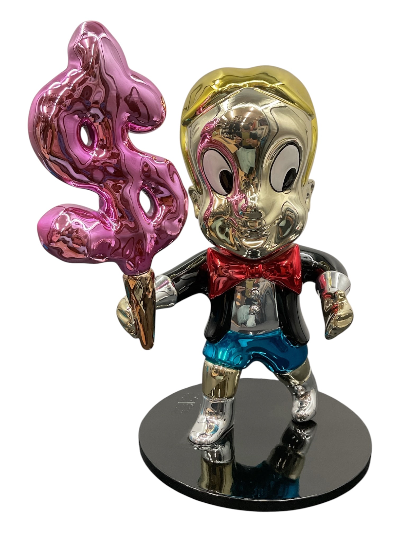 Contemporary “Richie Rich?? Style Pop Art Figure Sculpture: Contemporary pop art style sculpture depicting a youthful cartoon-inspired character in the manner of Richie Rich, rendered in a high-gloss metallic finish. The figure is shown holding an oversized pi