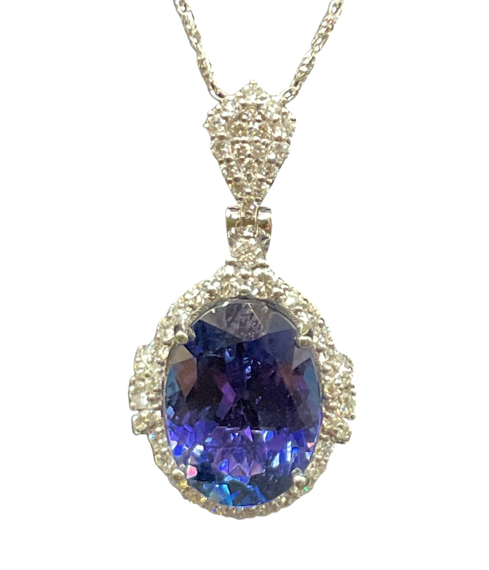 14K White Gold Tanzanite and Diamond Pendant Necklace: Striking and elegant, this fine jewelry pendant showcases a vivid oval-cut natural tanzanite set in 14K white gold, surrounded by a brilliant diamond halo. The center stone weighs approximately 6.85 c