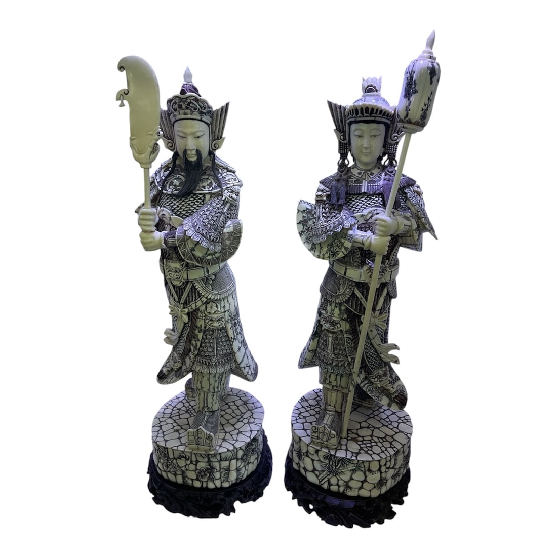 HC205 - Pair of Carved Asian Figures of Man and Woman Warriors: A finely detailed pair of carved figures depicting a male and female warrior, each presented in elaborate traditional armor and holding ceremonial weapons. These figures embody strength, protection, a