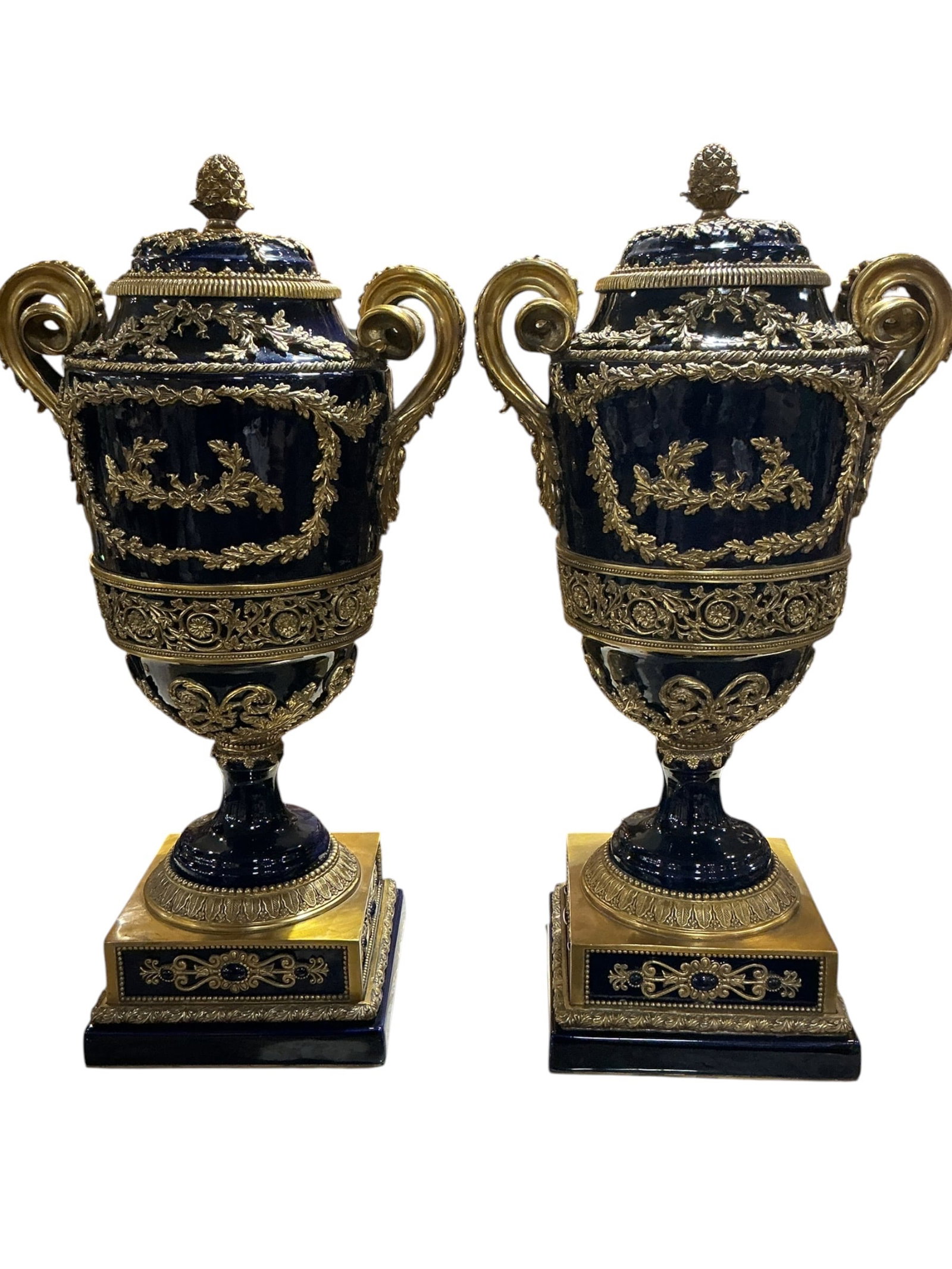PC448 - Pair of Cobalt Blue Porcelain and Dore Bronze Urns: A magnificent pair of cobalt blue porcelain urns lavishly mounted with dore bronze, executed in a classical European style. Each urn features a deep cobalt ground, providing a rich and dramatic