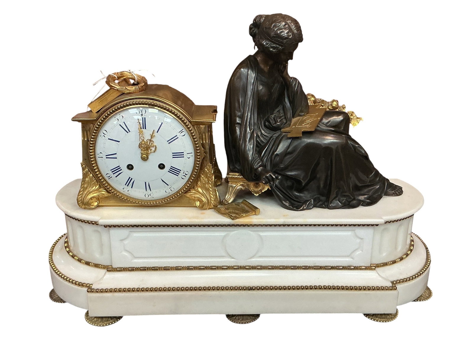 CK161- French White Marble and Bronze Figural Mantel Clock: An elegant French mantel clock crafted in white marble and adorned with finely cast bronze elements, featuring a sculptural figural composition. The clock is mounted with a seated female figure in pat