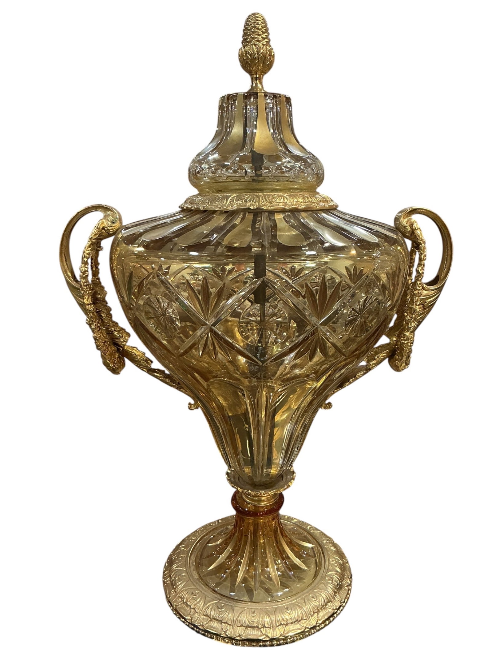 Crystal and Dore Bronze Mounted Urn: A richly detailed crystal urn enhanced with finely cast dore bronze mounts, executed in a classical European style. The body is formed in cut crystal with a warm amber tone, featuring deeply faceted g