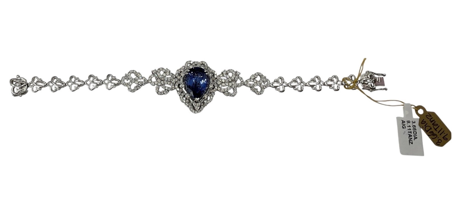 18K White Gold Sapphire and Diamond Bracelet with AIG Appraisal: An elegant bracelet crafted in 18K white gold, featuring a central heart-shaped blue sapphire framed by a halo of round brilliant cut diamonds. The design extends into a delicate lattice-style link br