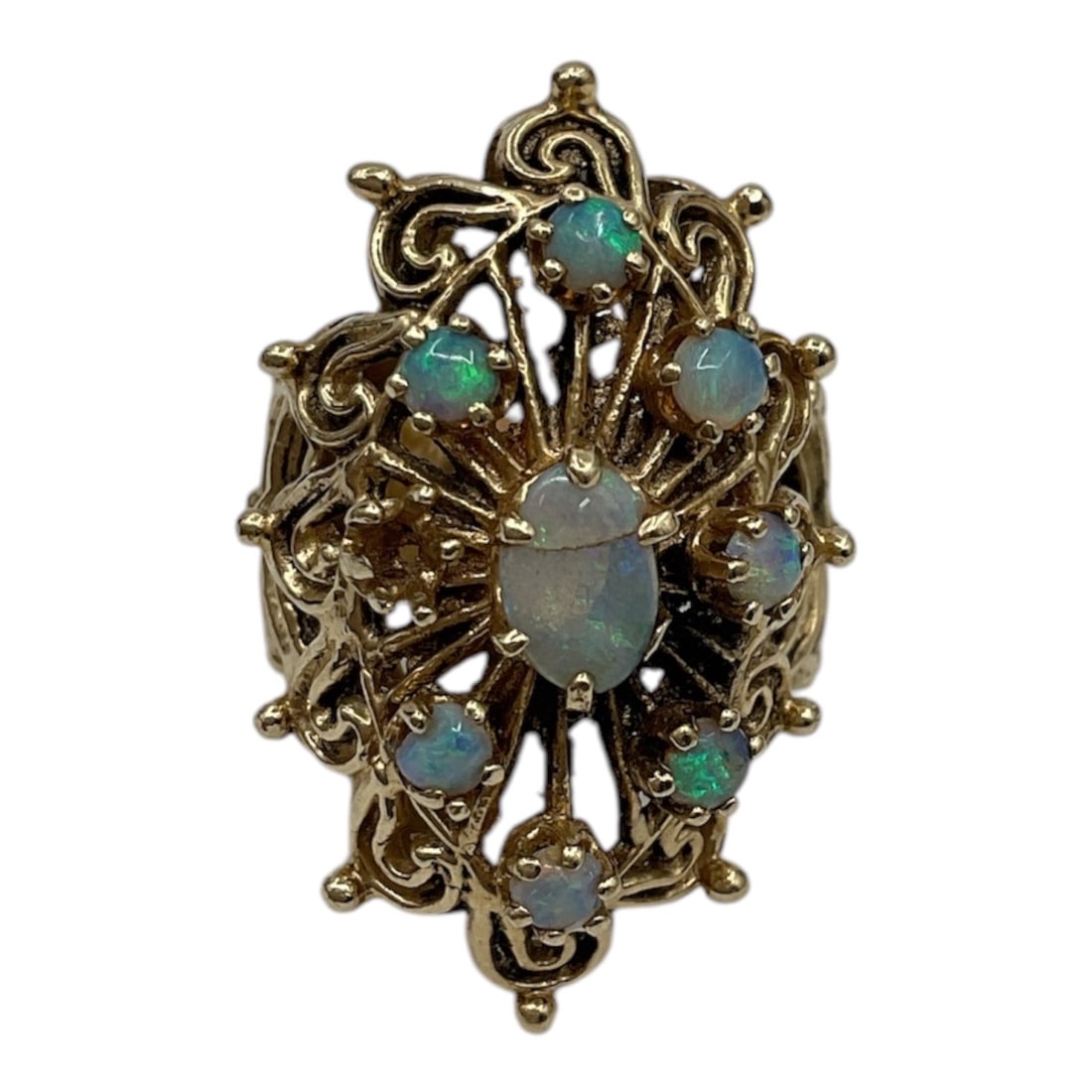 14K Gold Opal Cluster Ring: A 14 karat yellow gold ring featuring a decorative cluster of opals arranged in an ornate openwork setting. The ring displays a central opal surrounded by smaller opal stones set within intricate scro