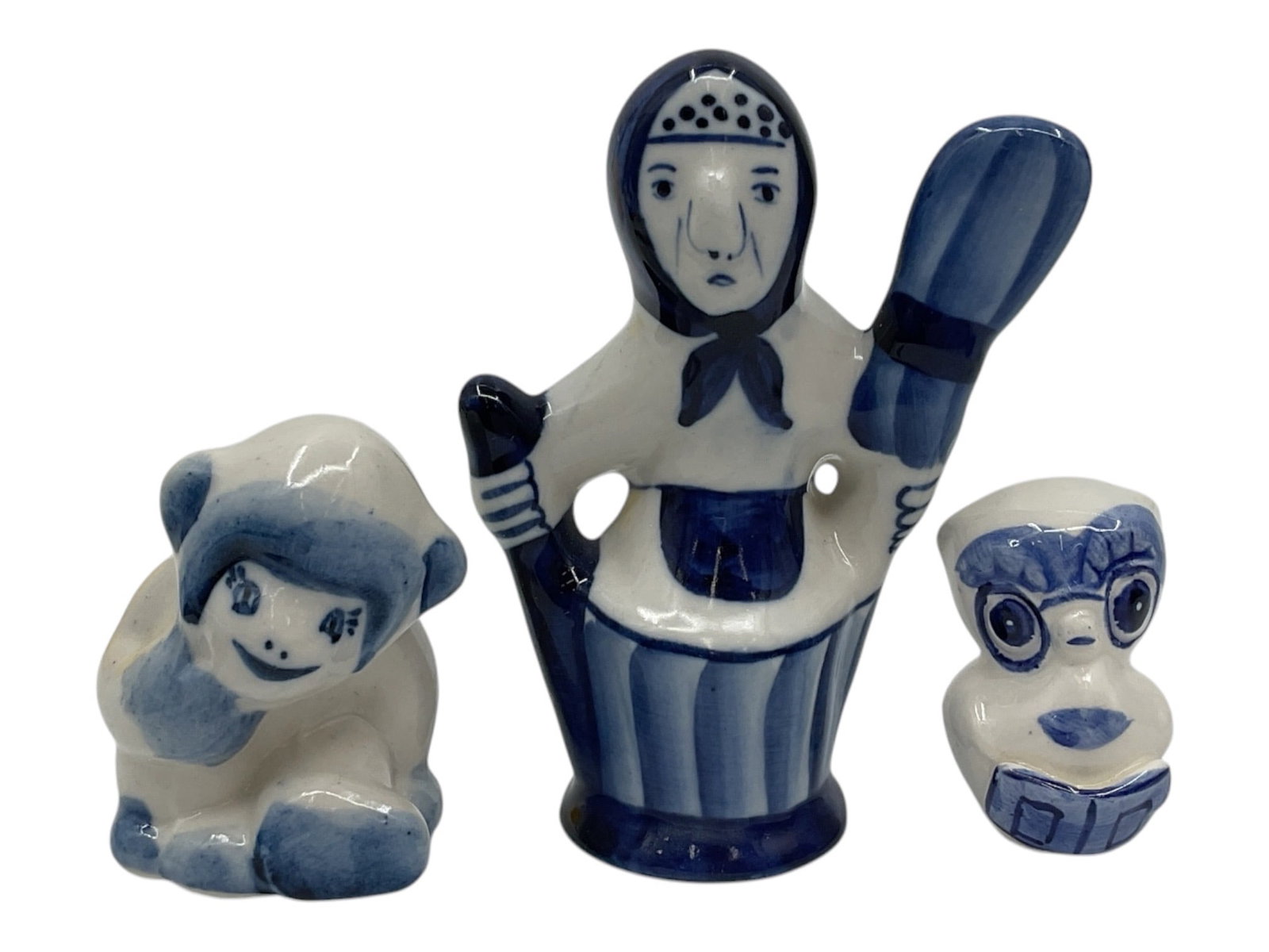 Group of Three Blue and White Ceramic Figurines: Decorative group of three blue and white ceramic figurines including a bonneted female figure and two stylized animal figures. Each features hand painted cobalt blue decoration with whimsical folk