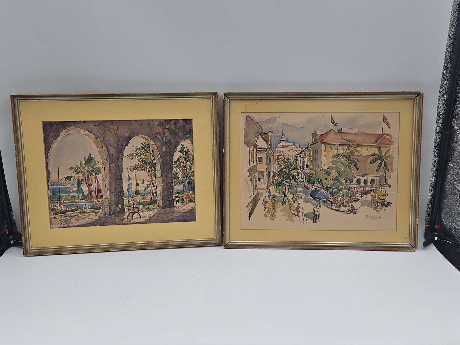 Mexican Street Scenes by Cecile Johnson: Pair of vibrant watercolor paintings depicting lively Mexican cityscapes, featuring colonial architecture, palm trees, and bustling market scenes. Cecile Johnson was known for her skillful use of