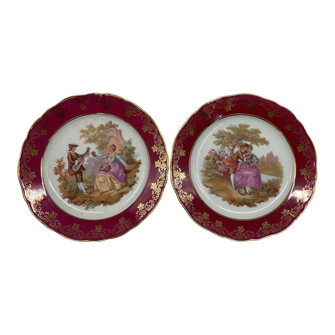 Pair of Limoges Porcelain Plates: Pair of vintage Limoges France porcelain cabinet plates featuring romantic courting scenes by artist Fragonard. Each plate is centered with finely detailed pastoral figural decoration and bordered by 