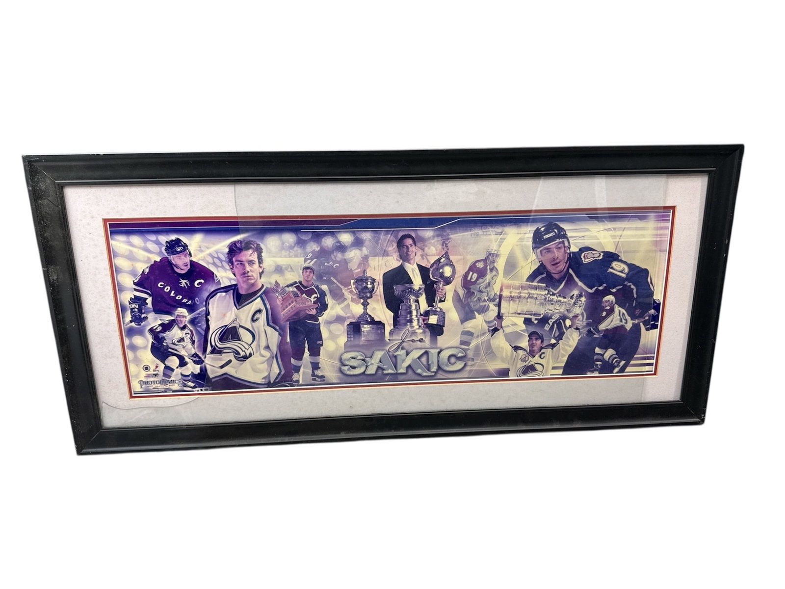 Framed Joe Sakic Colorado Avalanche Hockey Photo Collage Print: Large framed sports print celebrating NHL legend Joe Sakic, featuring a dramatic collage of action scenes, portrait imagery, and championship trophies from his career with the Colorado Avalanche. The