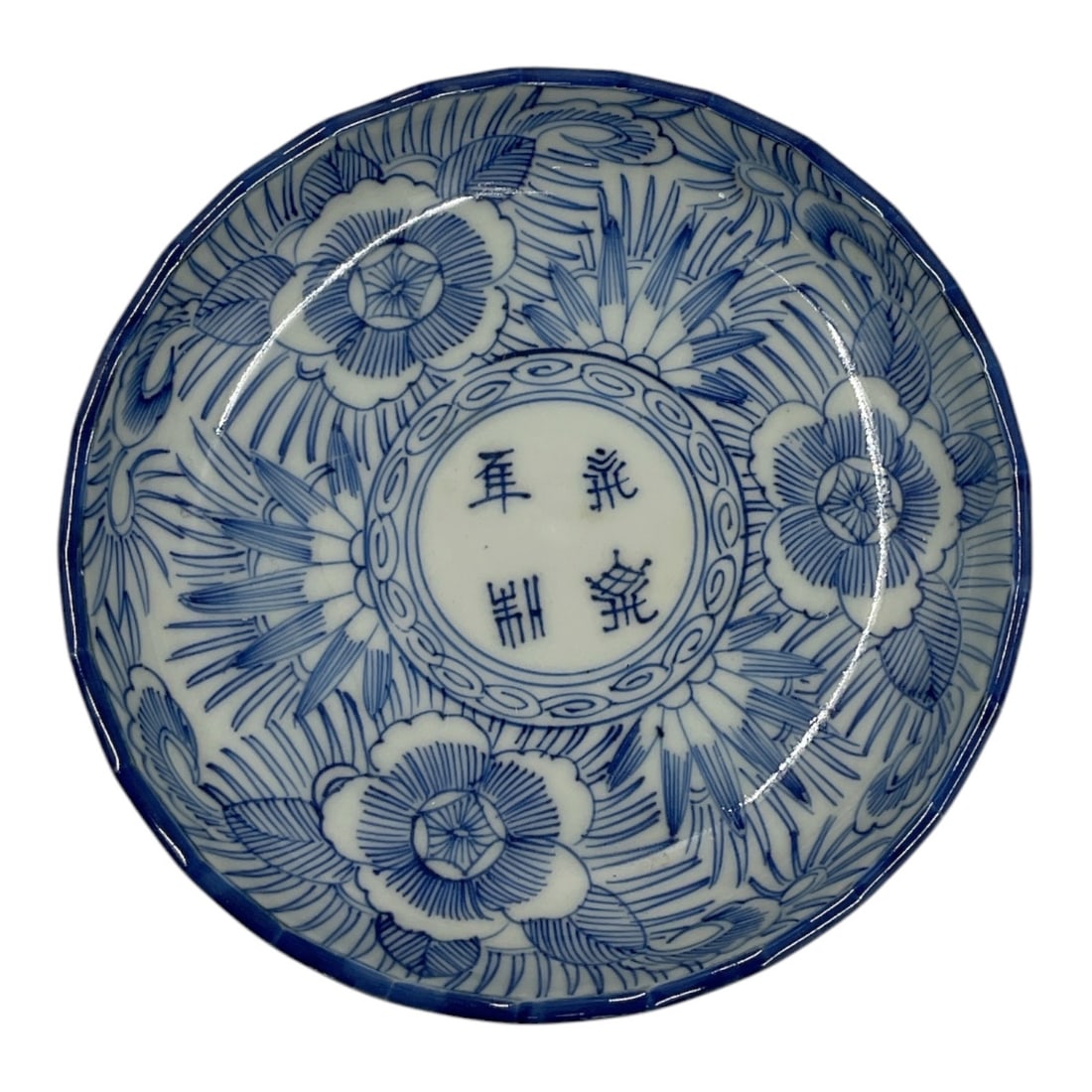 Chinese Blue and White Porcelain Bowl: Chinese porcelain bowl decorated in underglaze blue with stylized floral blooms, foliage, and a central roundel containing Chinese characters. The exterior features complementary blue decorative borde