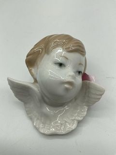Lladro Seraph's Head No. 2 Figurine: A glazed porcelain bust of a young cherub with soft facial features, golden hair, and detailed outstretched wings. Dimensions: H3in L3in Medium: Glazed porcelain