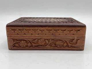 Hand-Carved Wooden Trinket Box with Inlaid Floral Motif: Decorative hand-carved wooden trinket box with detailed floral pattern and contrasting inlay on the lid. Interior lined in dark blue velvet. Dimensions: H: 3in L: 7in W: 5in Medium: Wood with