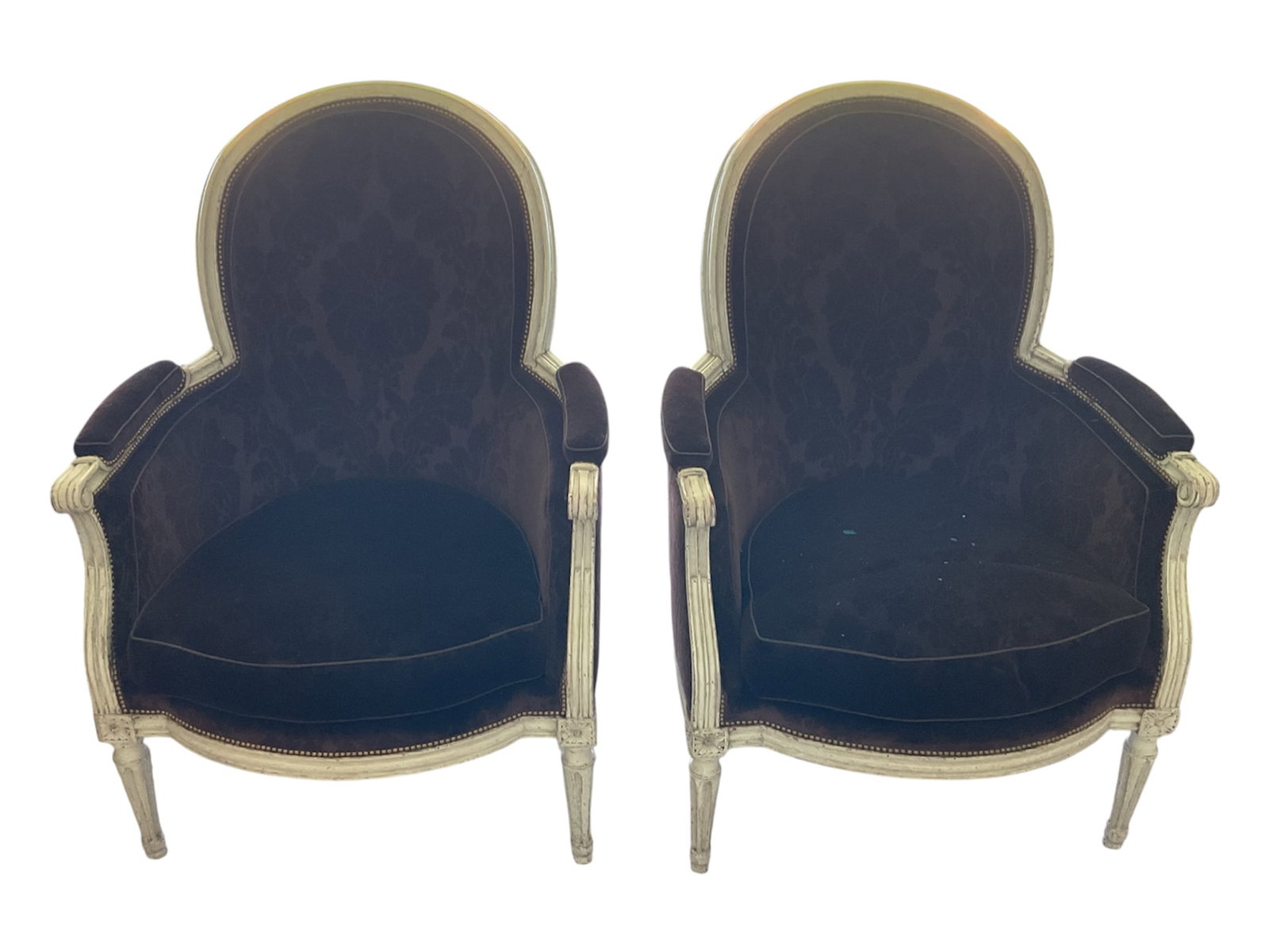 18th-century French Louis XVI-style velvet bergère armchairs, set of 2: A handsome pair of French Louis XVI-style bergère armchairs featuring tall rounded upholstered backs, enclosed upholstered sides, padded armrests, and loose seat cushions. The chairs are uphols