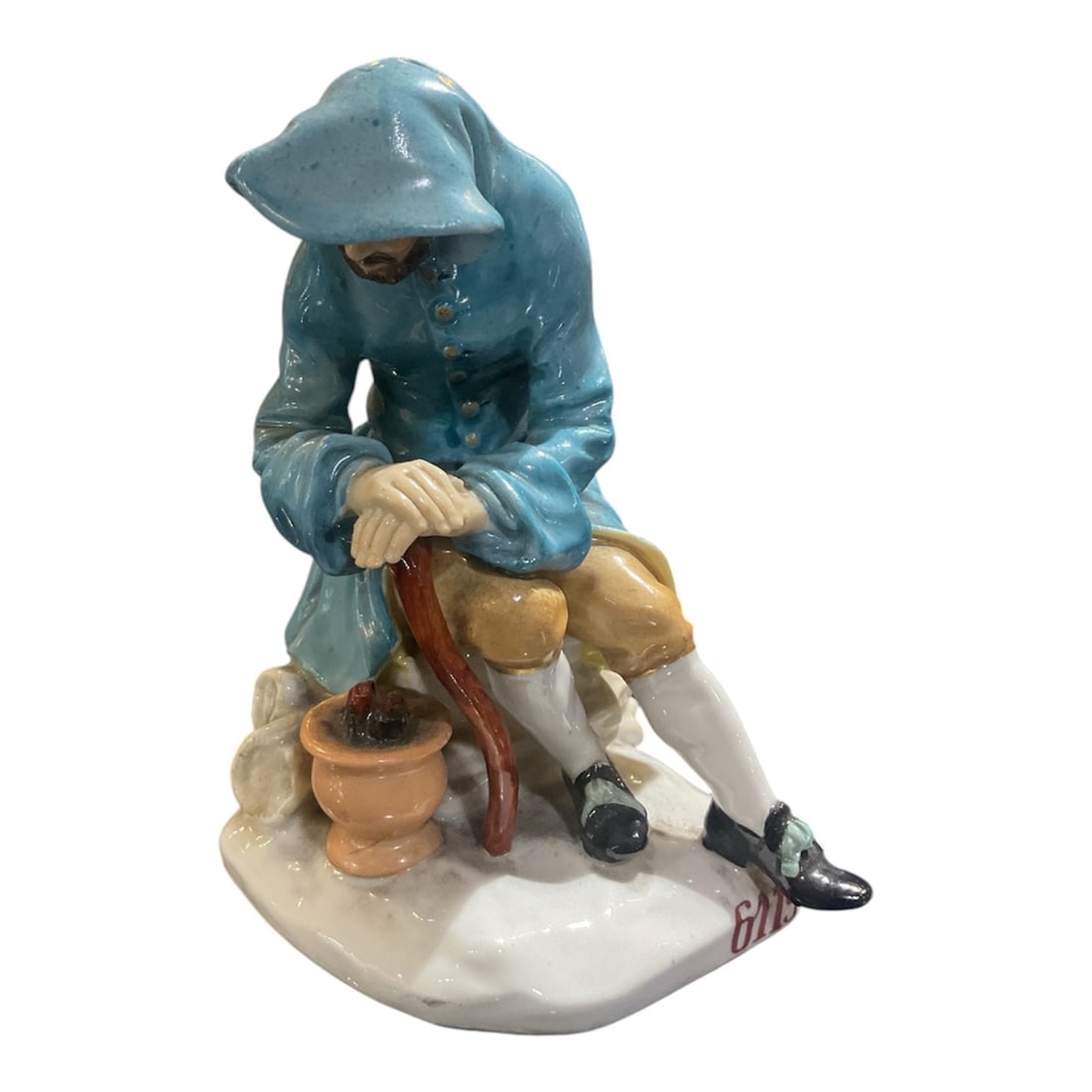 PC485 - Dresden Porcelain Figure of Seated Man with Cane: A finely modeled Dresden porcelain figure depicting a seated man in traditional European attire, rendered with expressive detail and hand-painted decoration. The figure captures a quiet, contemplative