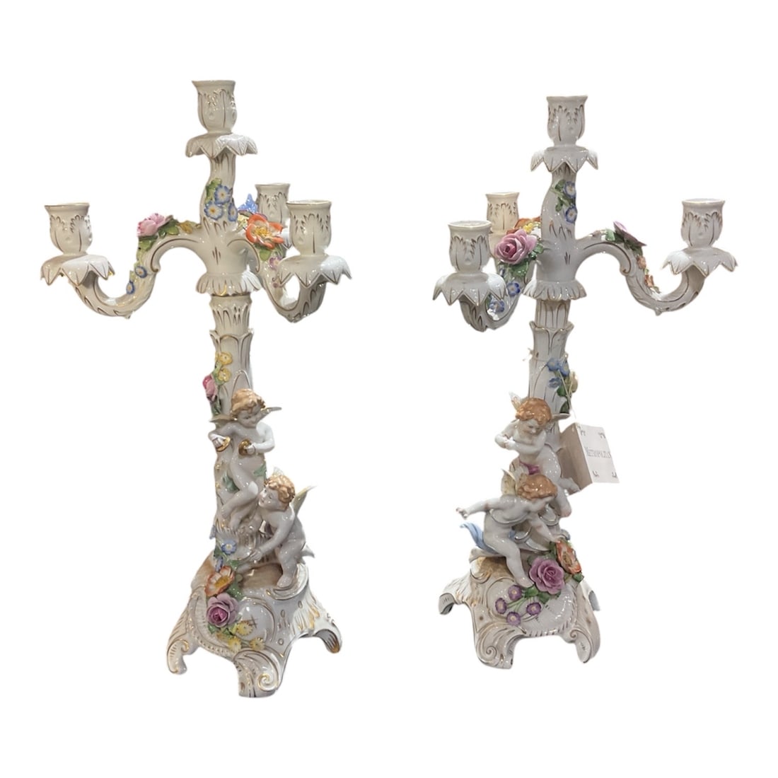 PC515 - Pair of 19th Century Dresden Porcelain Figural Candelabras: An exquisite pair of Dresden porcelain candelabra, richly decorated with sculptural cherub figures, applied floral elements, and multi-arm candle branches in the tradition of 19th century European dec