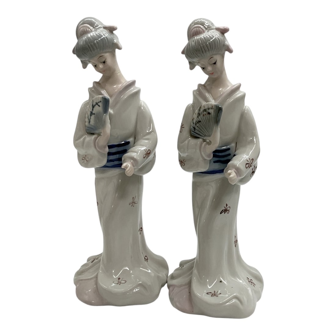 Geisha Porcelain Figurines with Fans, Pair: Vintage pair of porcelain figurines depicting elegant Japanese women in traditional kimono-style robes, each holding a folding fan. Finished in a glossy white glaze with delicate hand-painted floral a