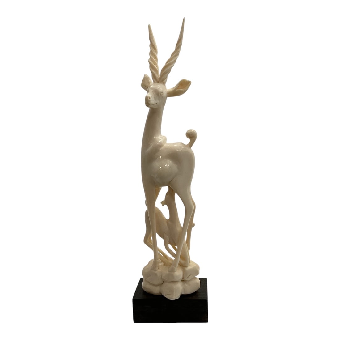 Asian-Style Carved Antelope Figural Sculpture: A decorative Asian-style carved sculpture depicting a graceful standing antelope or gazelle with long spiraled horns. The animal is posed atop a naturalistic openwork base with carved rock and