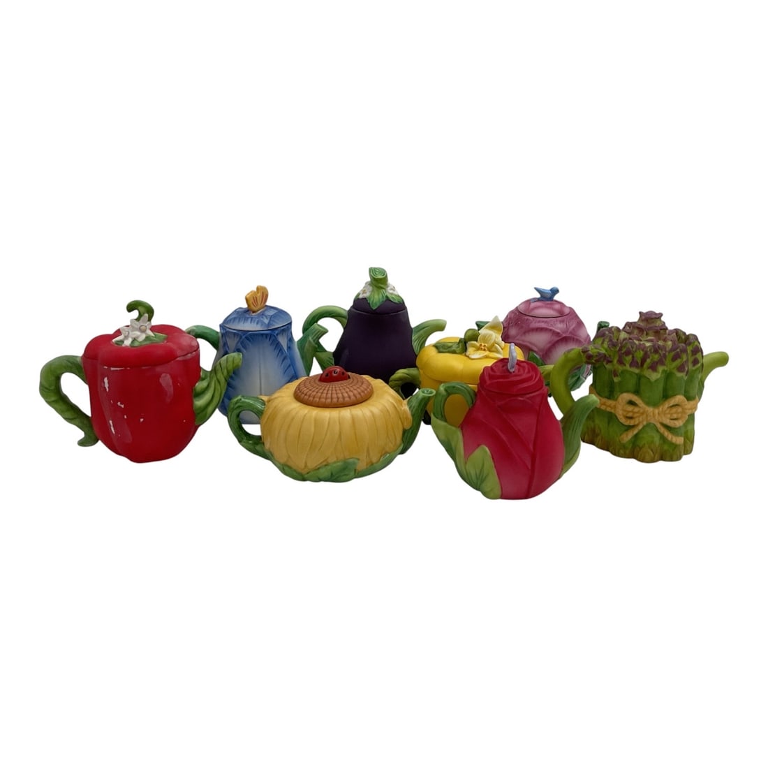 1996 Avon Season's Harvest Fruit & Vegetable Ceramic Teapot Collection: A colorful collection of vintage Avon Season's Harvest ceramic novelty teapots dating to 1996. The group features whimsical fruit, vegetable, and floral forms, including designs resembling an