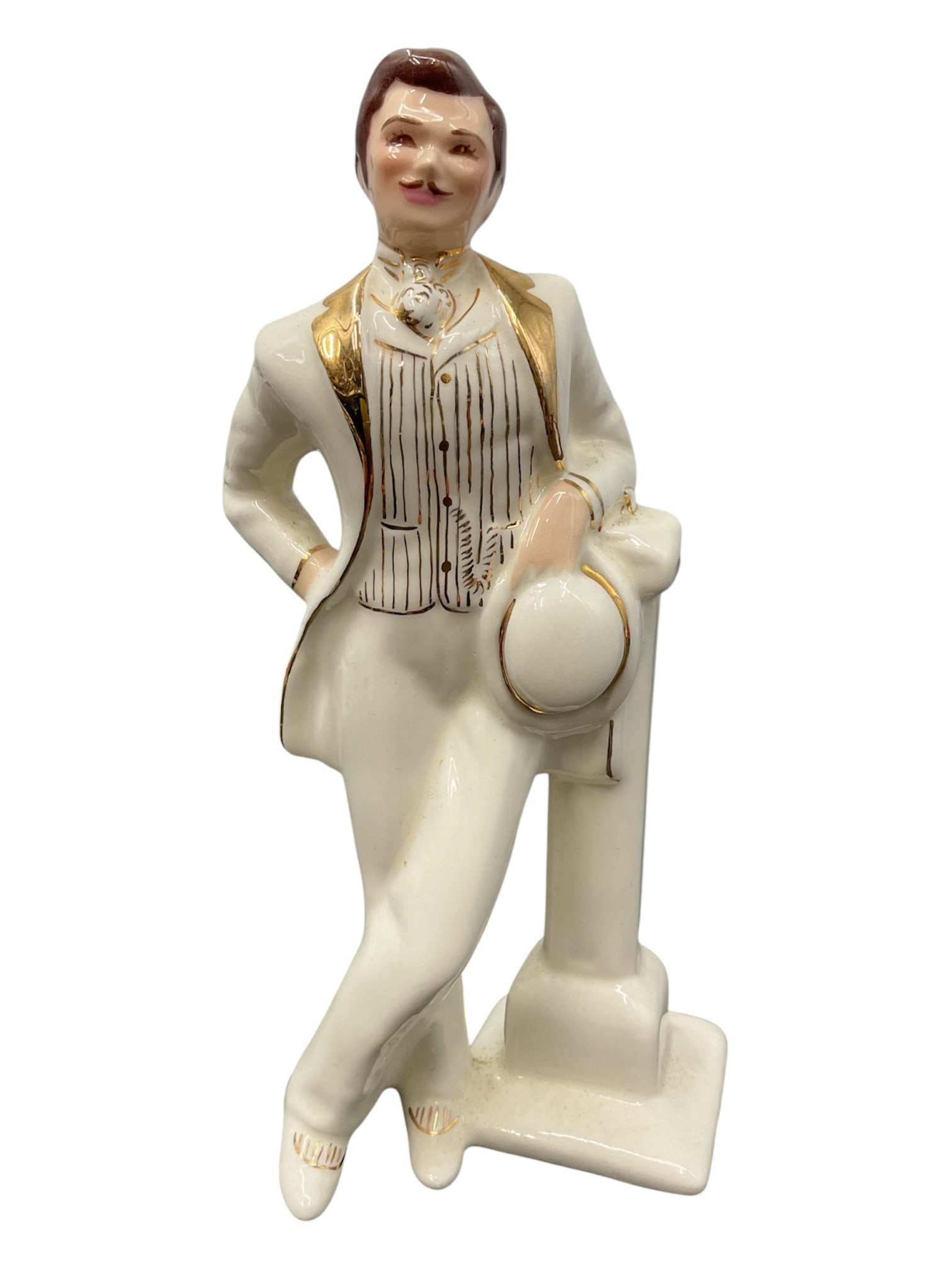 Florence Ceramics Gentleman Figure, Pasadena California: Charming mid-century porcelain figurine by Florence Ceramics of Pasadena, California, depicting a well-dressed gentleman in a relaxed pose. The figure leans casually against a pedestal, holding a hat,