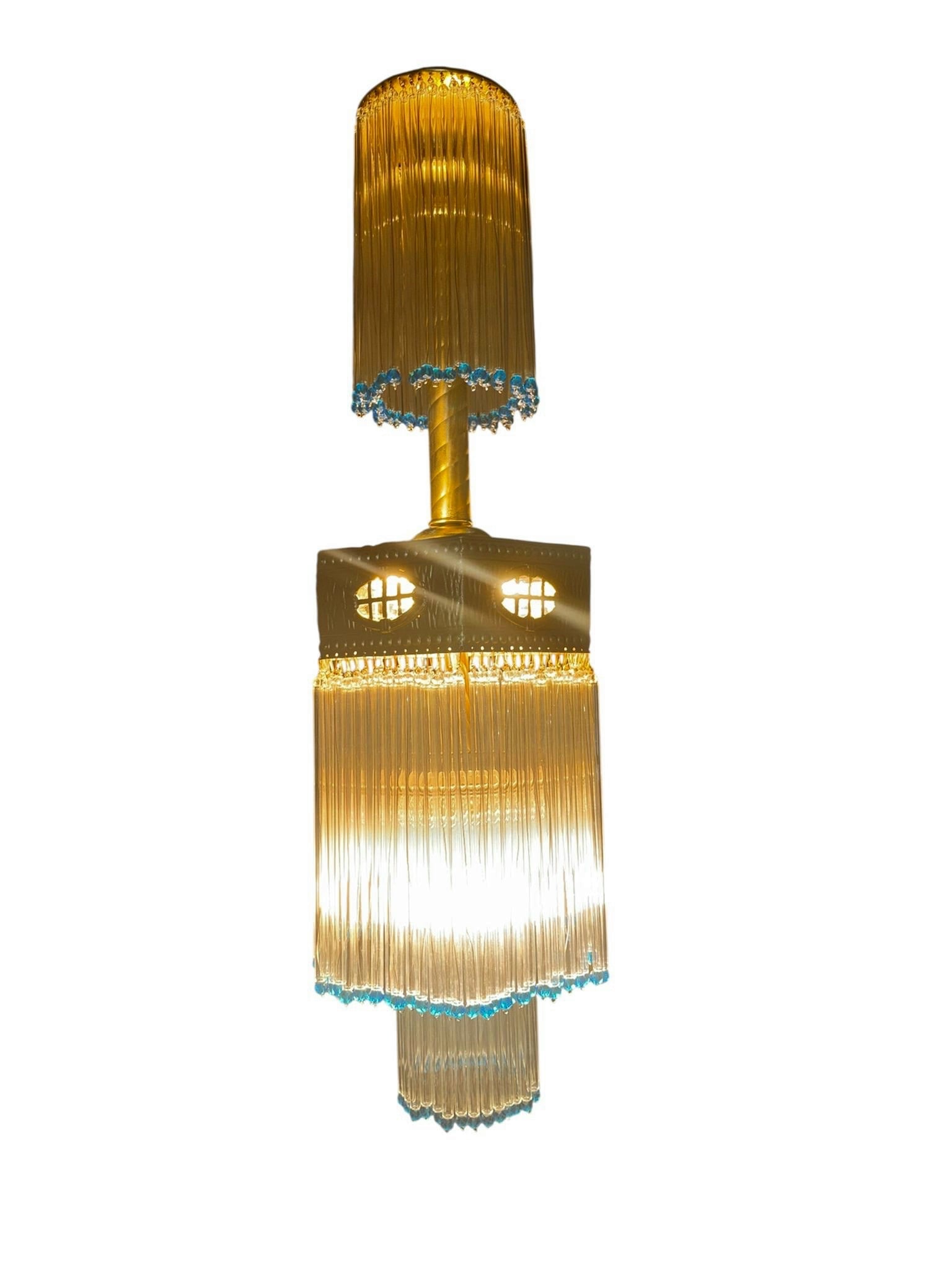 Vintage Art Deco Chandelier: This vintage Art Deco chandelier features a multi-tiered design with a central brass or gilded metal body and elongated glass rod accents. The upper section consists of a cylindrical glass rod shade t