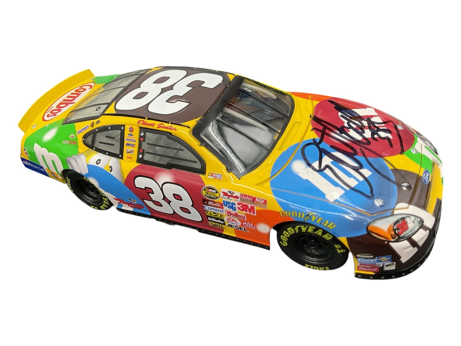Signed Elliott Sadler No. 38 M&M’s NASCAR Ford Taurus 1:24 Die-Cast Race Car: Signed NASCAR collectible die-cast race car featuring Elliott Sadler’s No. 38 Ford Taurus in the colorful M&M’s racing livery. The car features the signature M&M’s candy