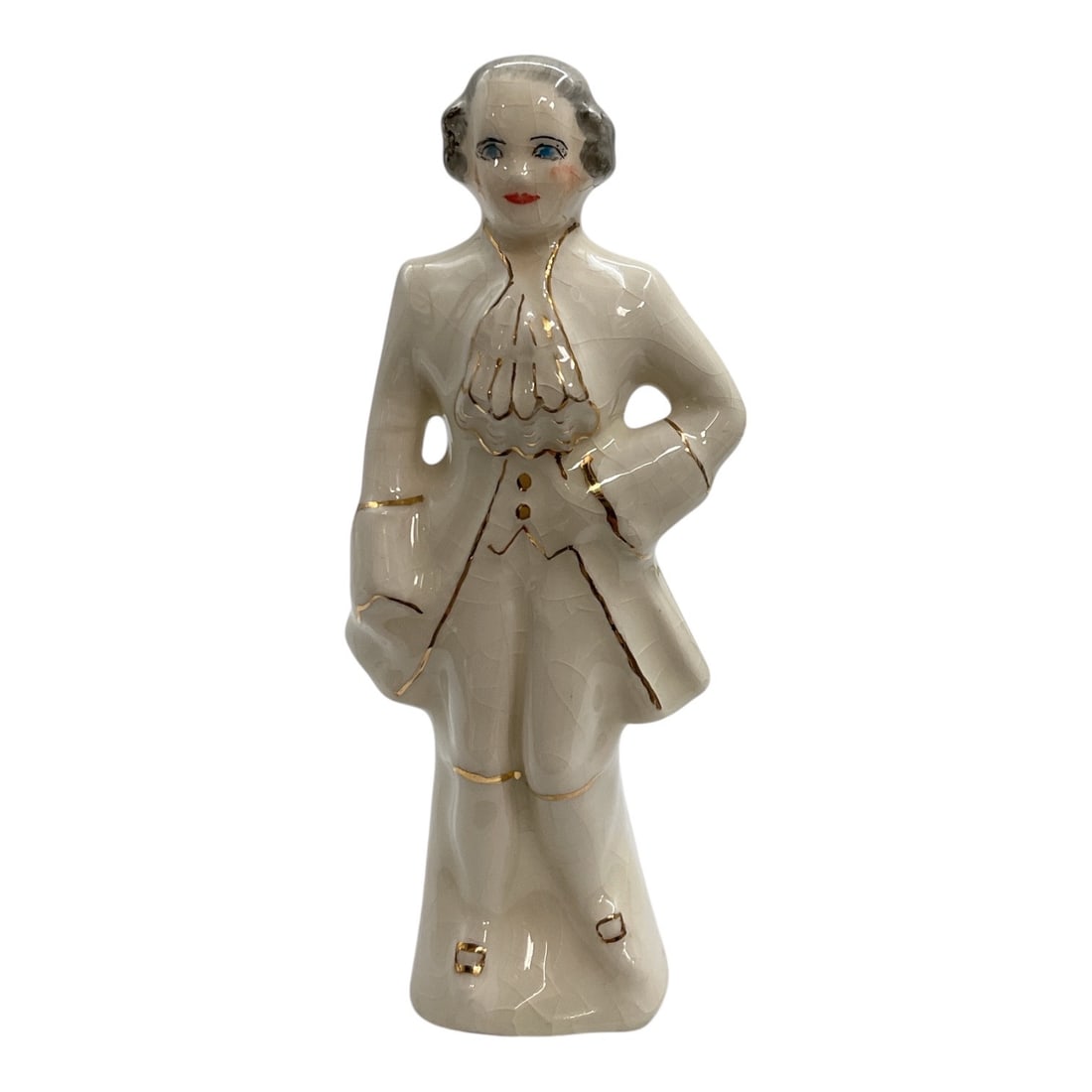 Vintage Porcelain Gentleman Figurine with Gold Accents: Vintage porcelain figurine depicting an elegantly dressed gentleman in formal attire. The figure is modeled standing with one hand at his waist and the other holding a hat, dressed in a cream-colored